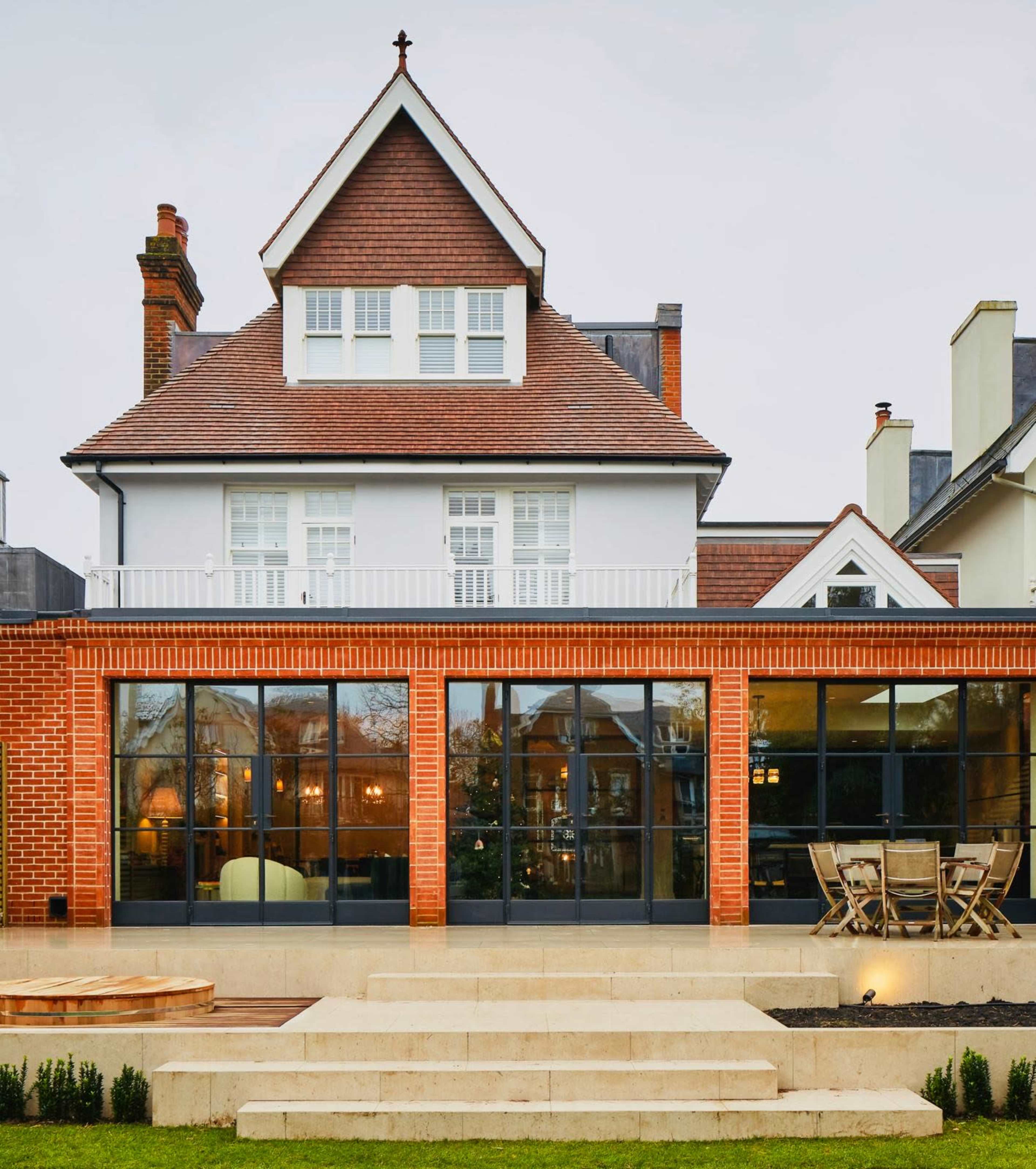 A two-story house features a brick exterior with large glass windows and a tiered outdoor area.