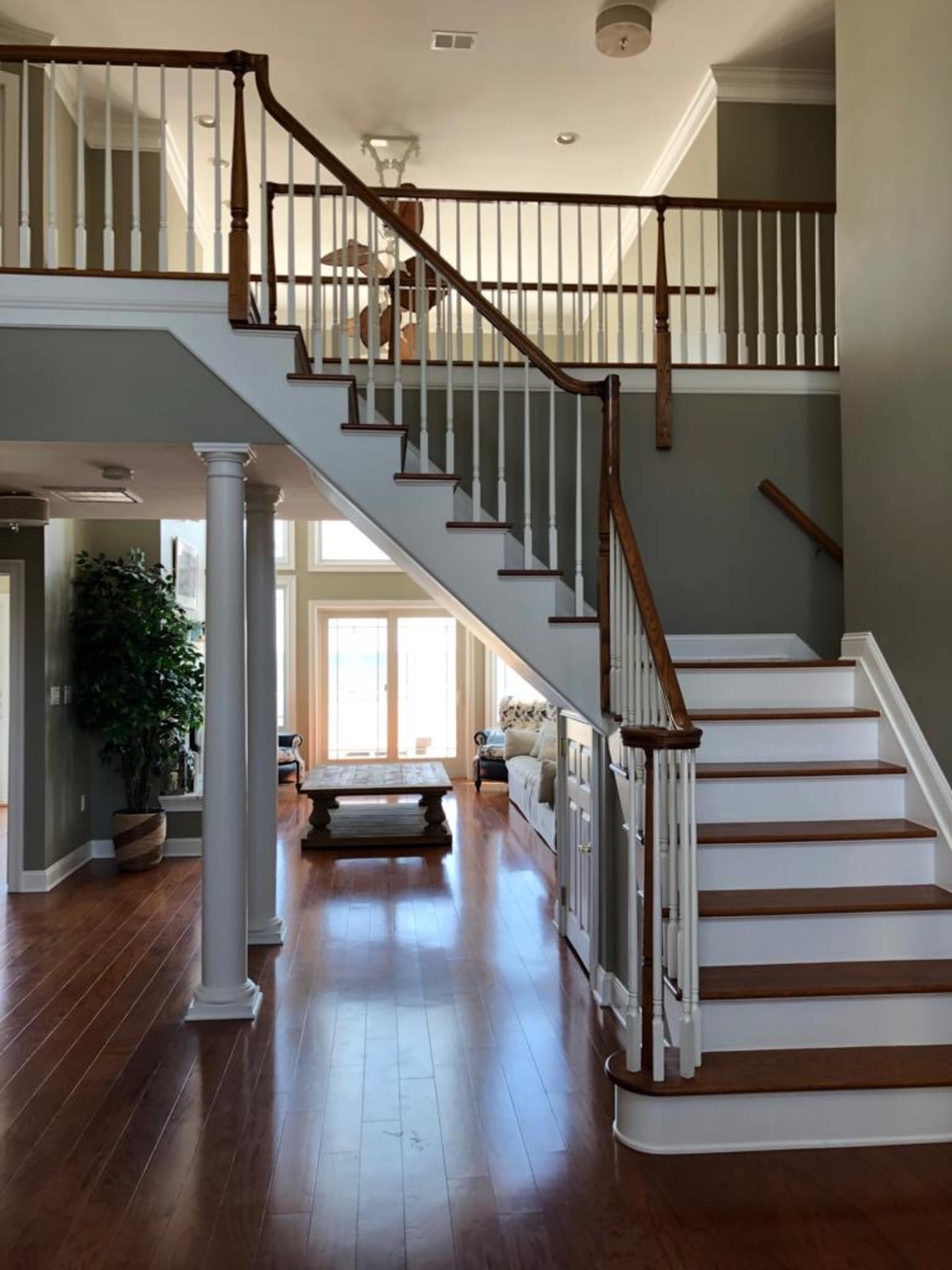 A spacious entryway with a staircase leading to an upper level, flanked by white railings and wooden accents.