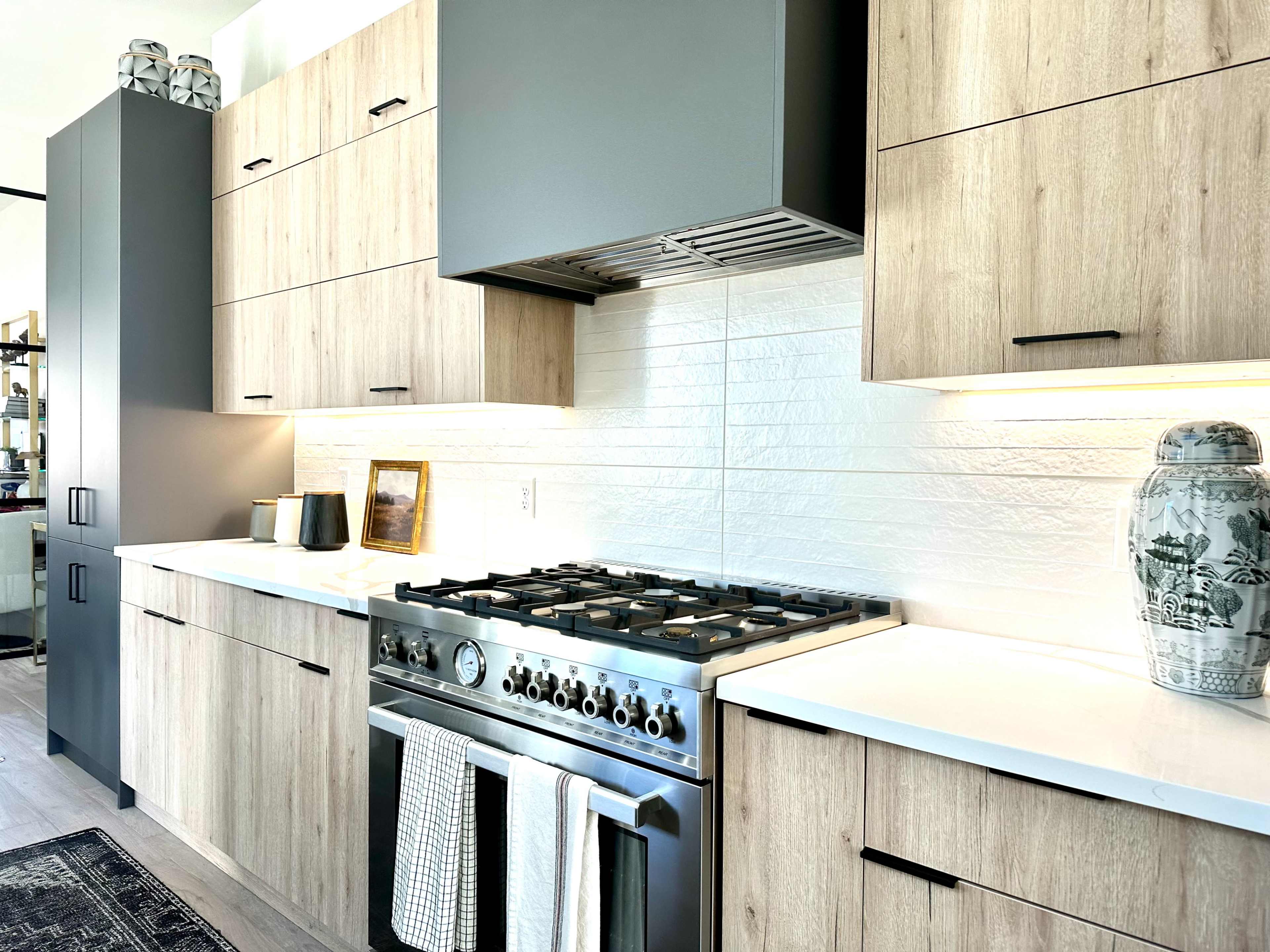 A modern kitchen with wooden cabinets, a stainless steel gas range, and a white tiled backsplash.