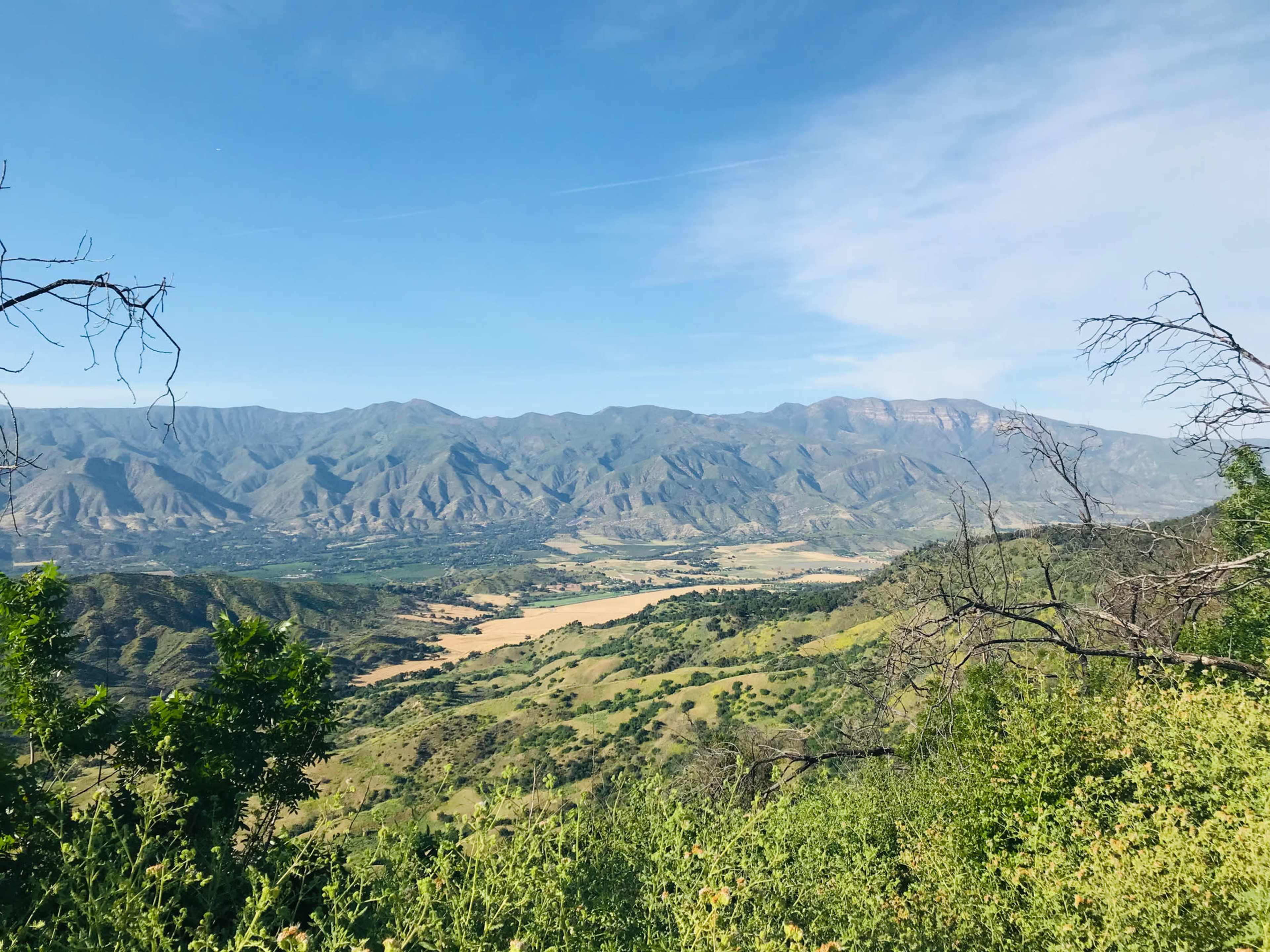 A panoramic view of a valley surrounded by mountains under a clear blue sky.