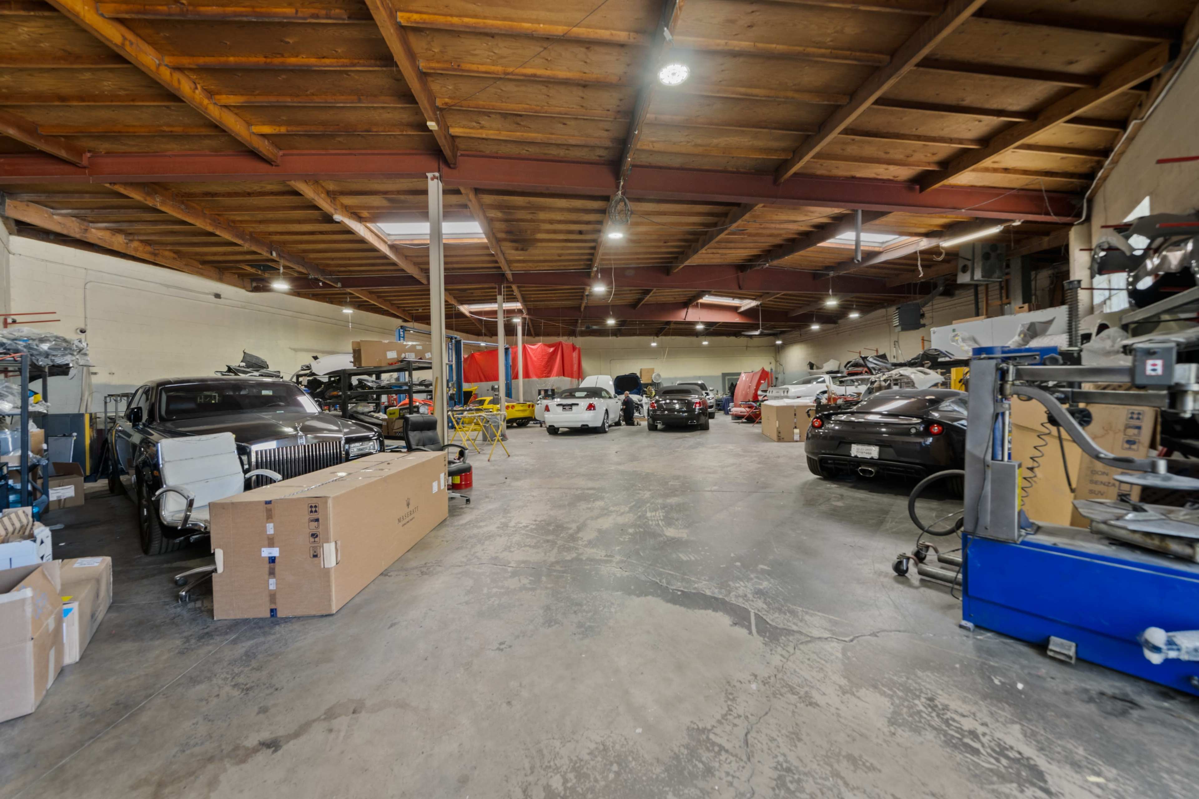 An interior garage or workshop with several vehicles, boxes, and equipment arranged throughout the space.