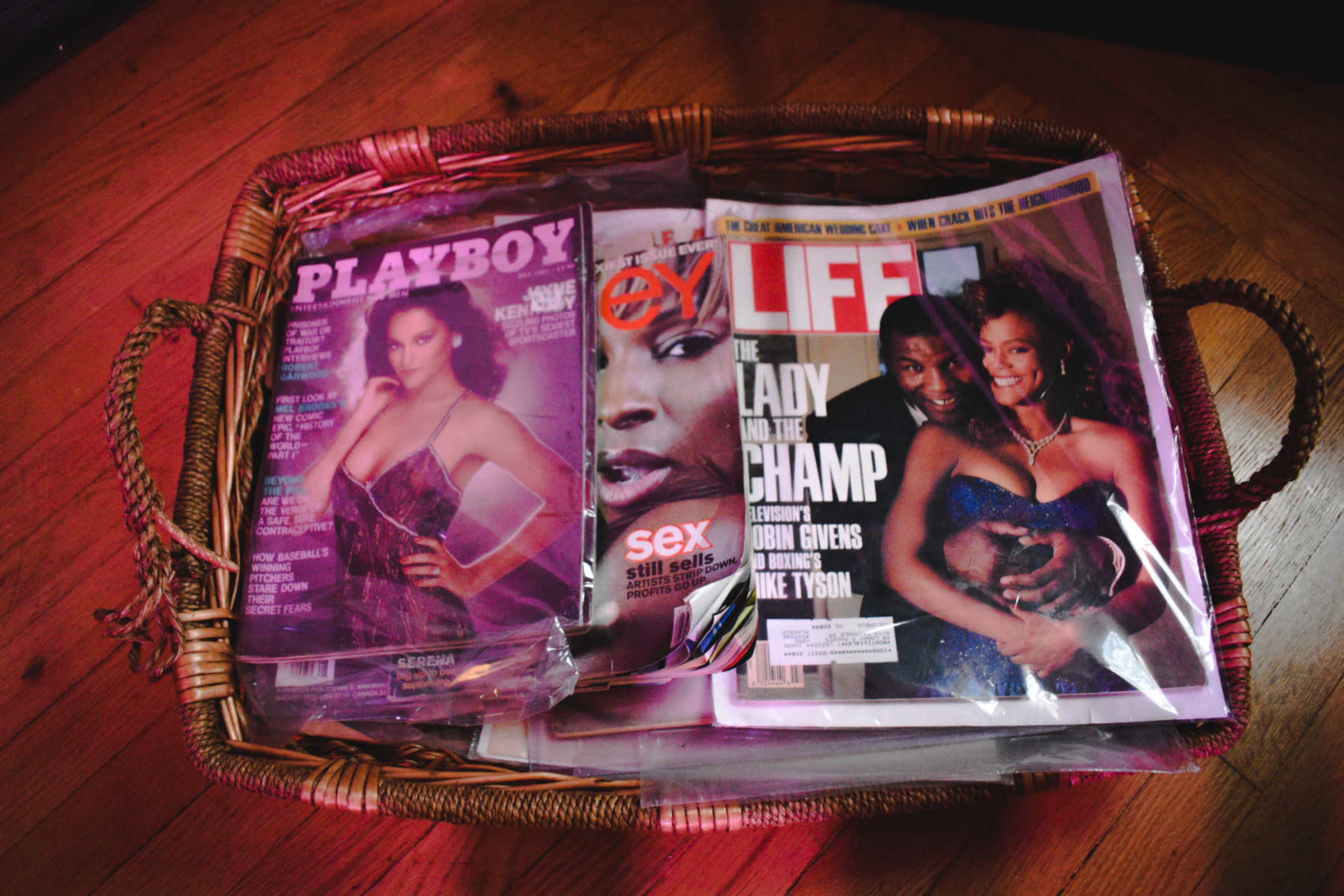 A wicker basket contains various magazines, including "Playboy," "Eye," and "Life," featuring notable figures on the covers.