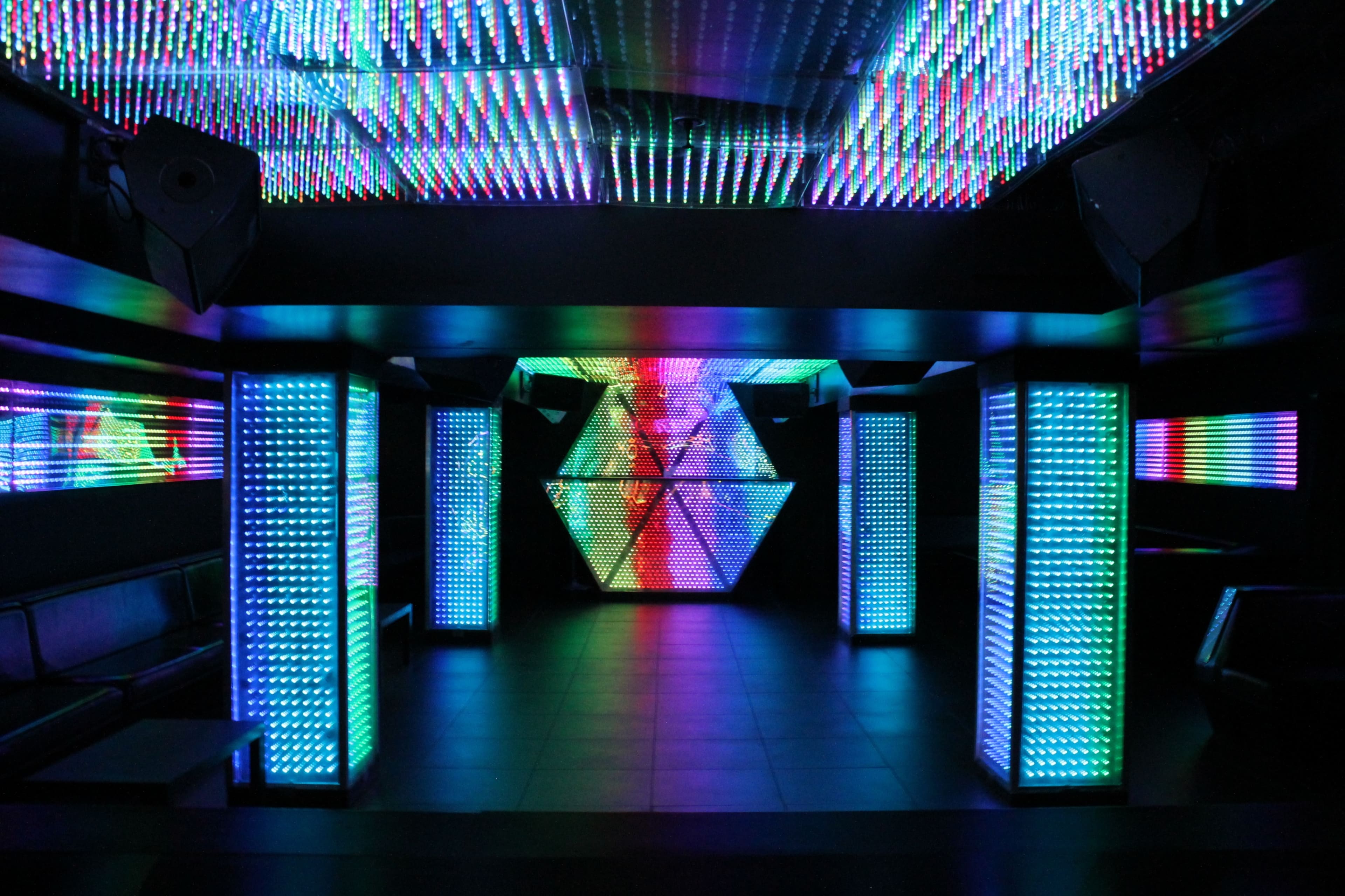 A modern nightclub interior featuring colorful LED light displays on the walls and pillars.