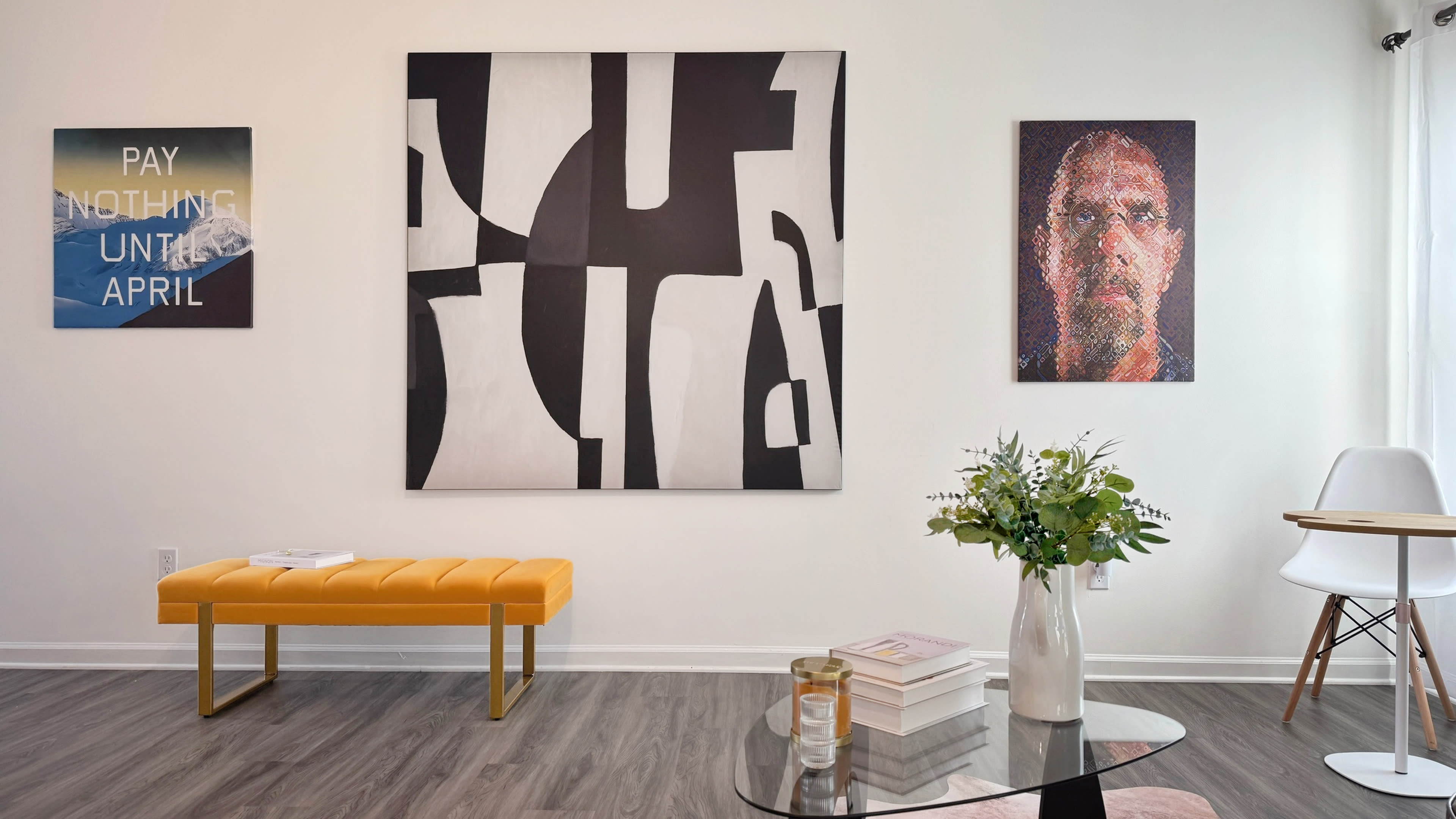 The image shows a modern interior with a yellow bench, a glass coffee table, and abstract artwork on the walls.