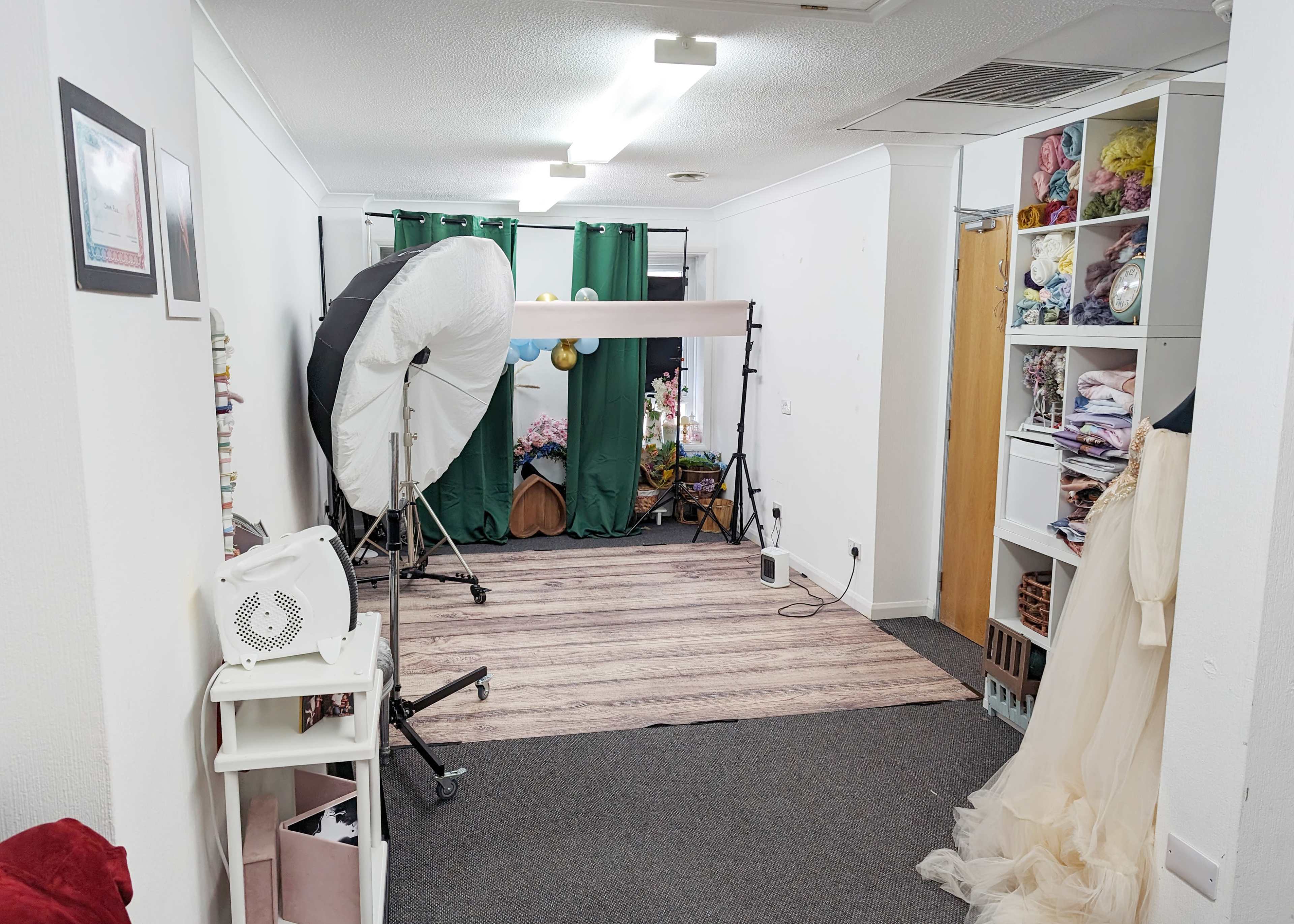 A photography studio with lighting equipment, a backdrop, and shelves filled with fabric.