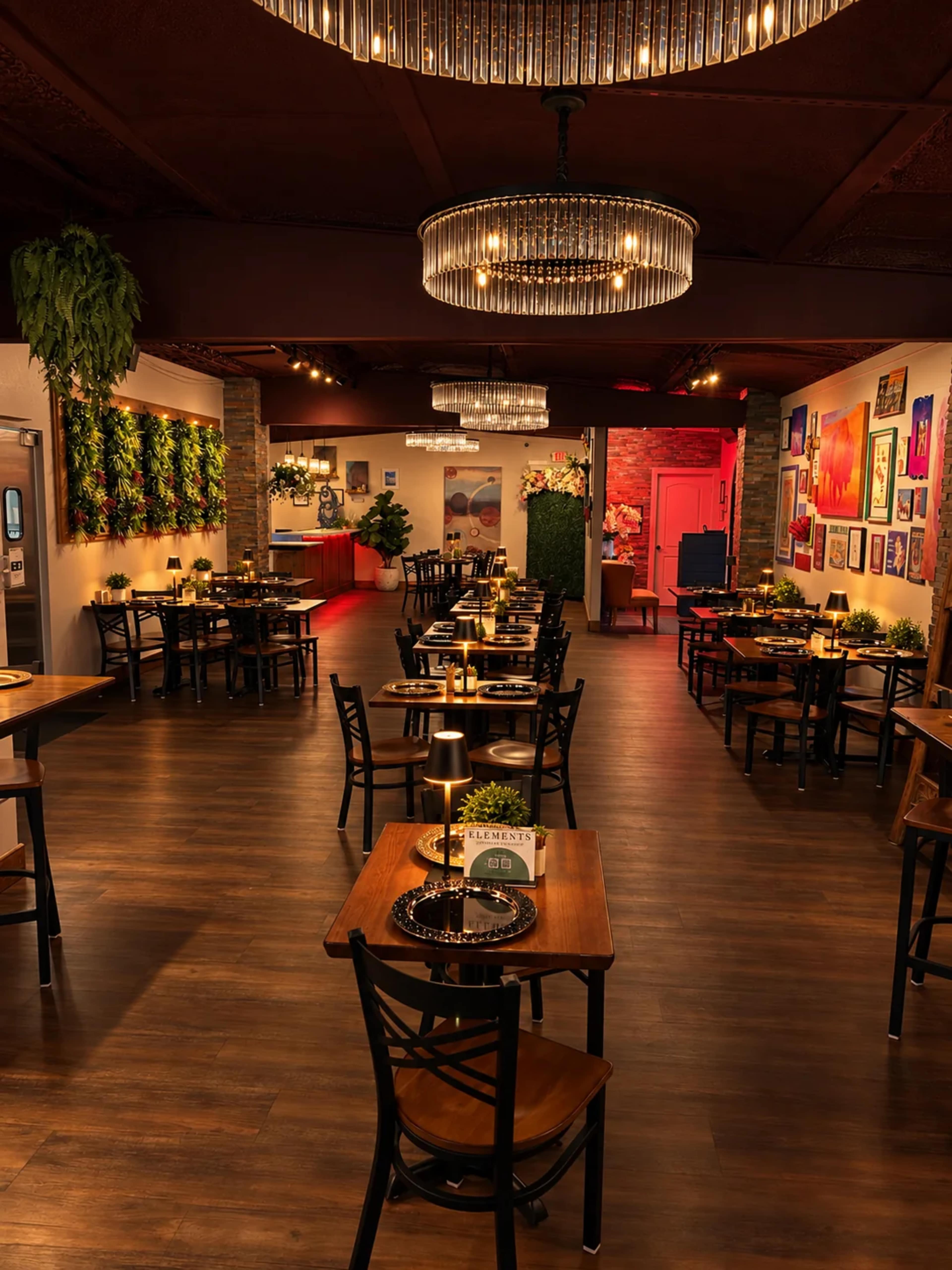The image depicts a restaurant interior featuring wooden tables arranged with small lamps, greenery on the walls, and colorful artwork decorating the surrounding space.