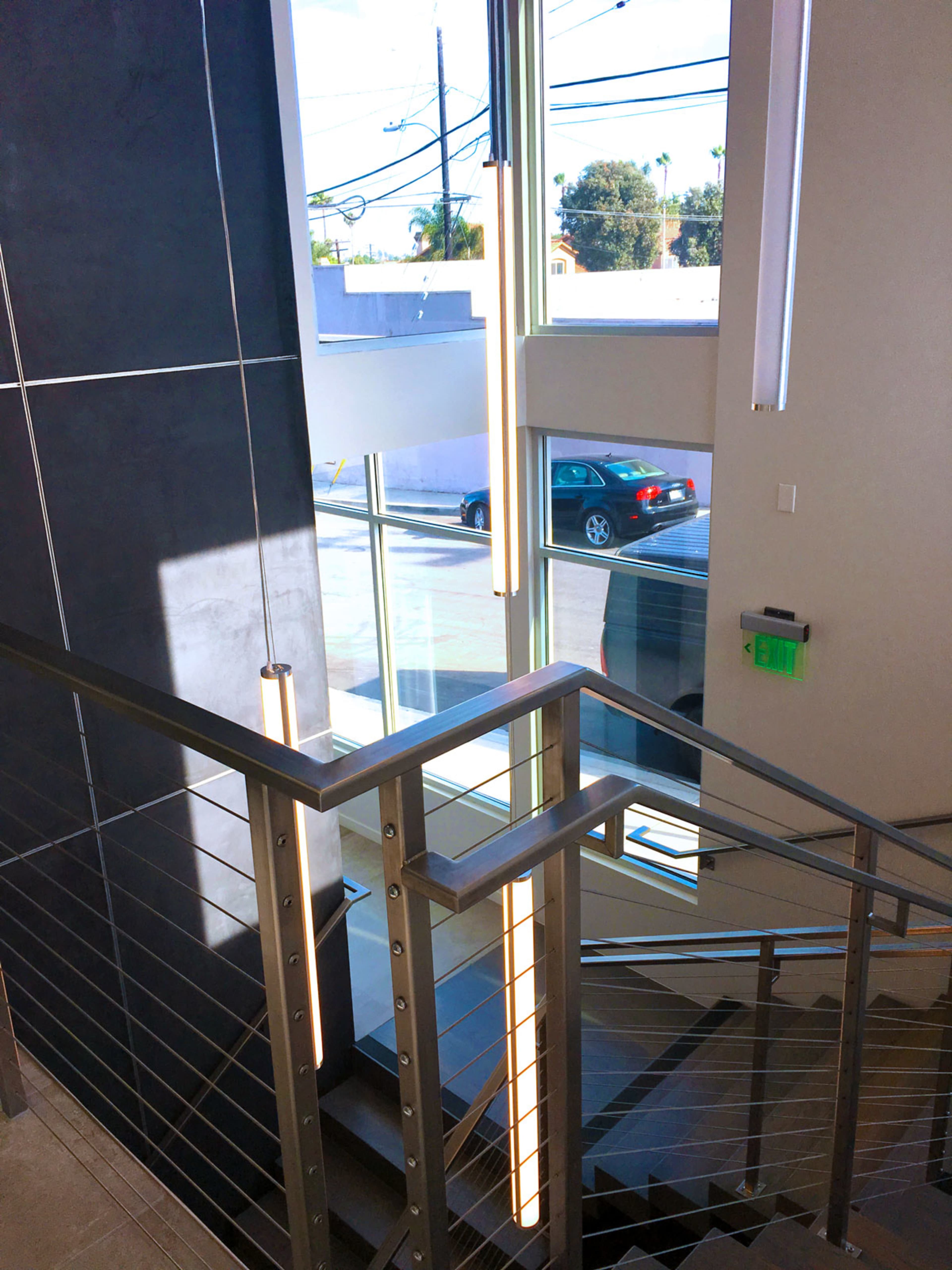 A staircase with a metal railing, leading down to a large window displaying a car parked outside.