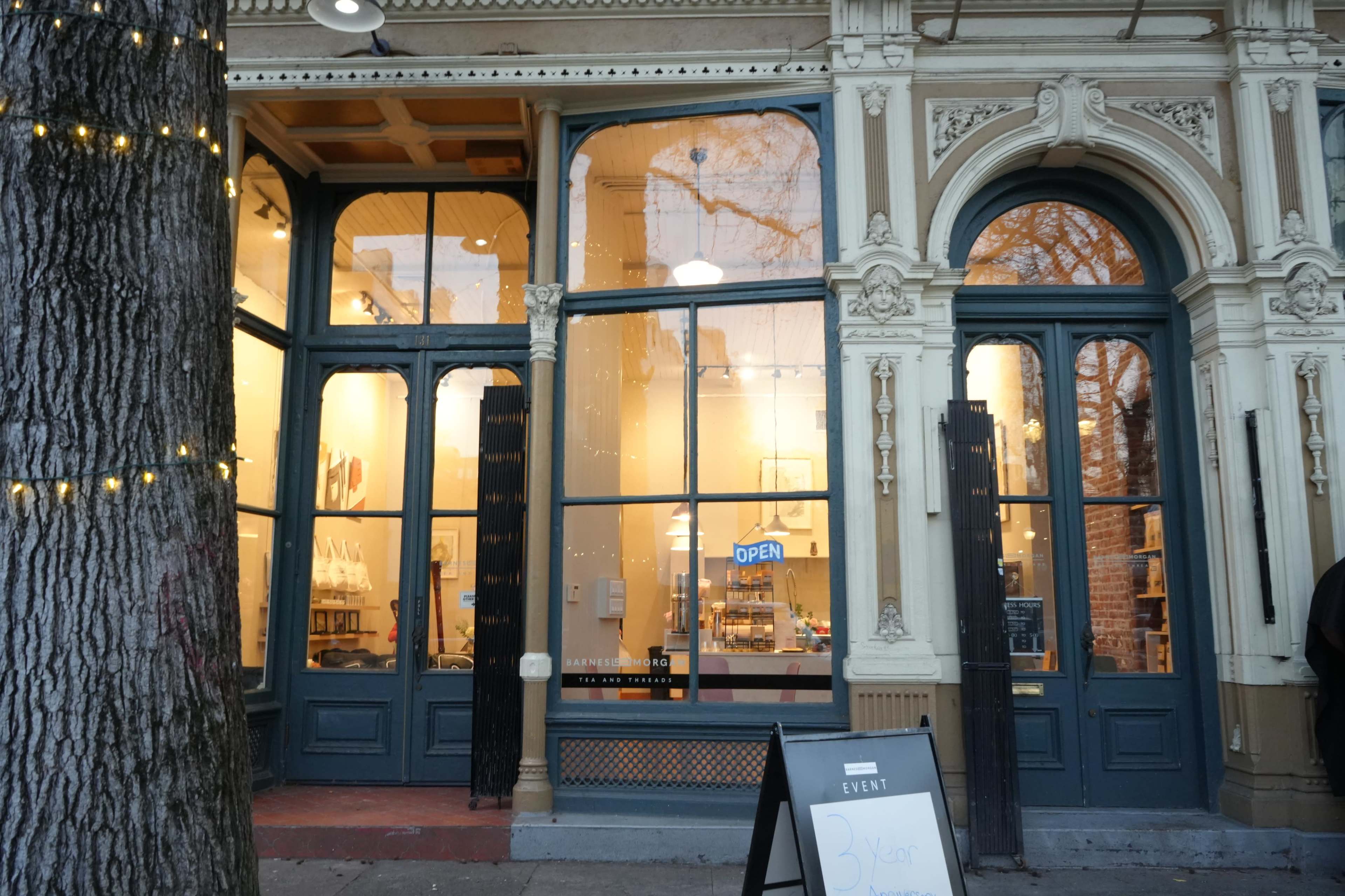 The image shows the exterior of a storefront featuring large glass windows with an "OPEN" sign, framed by decorative architectural elements.
