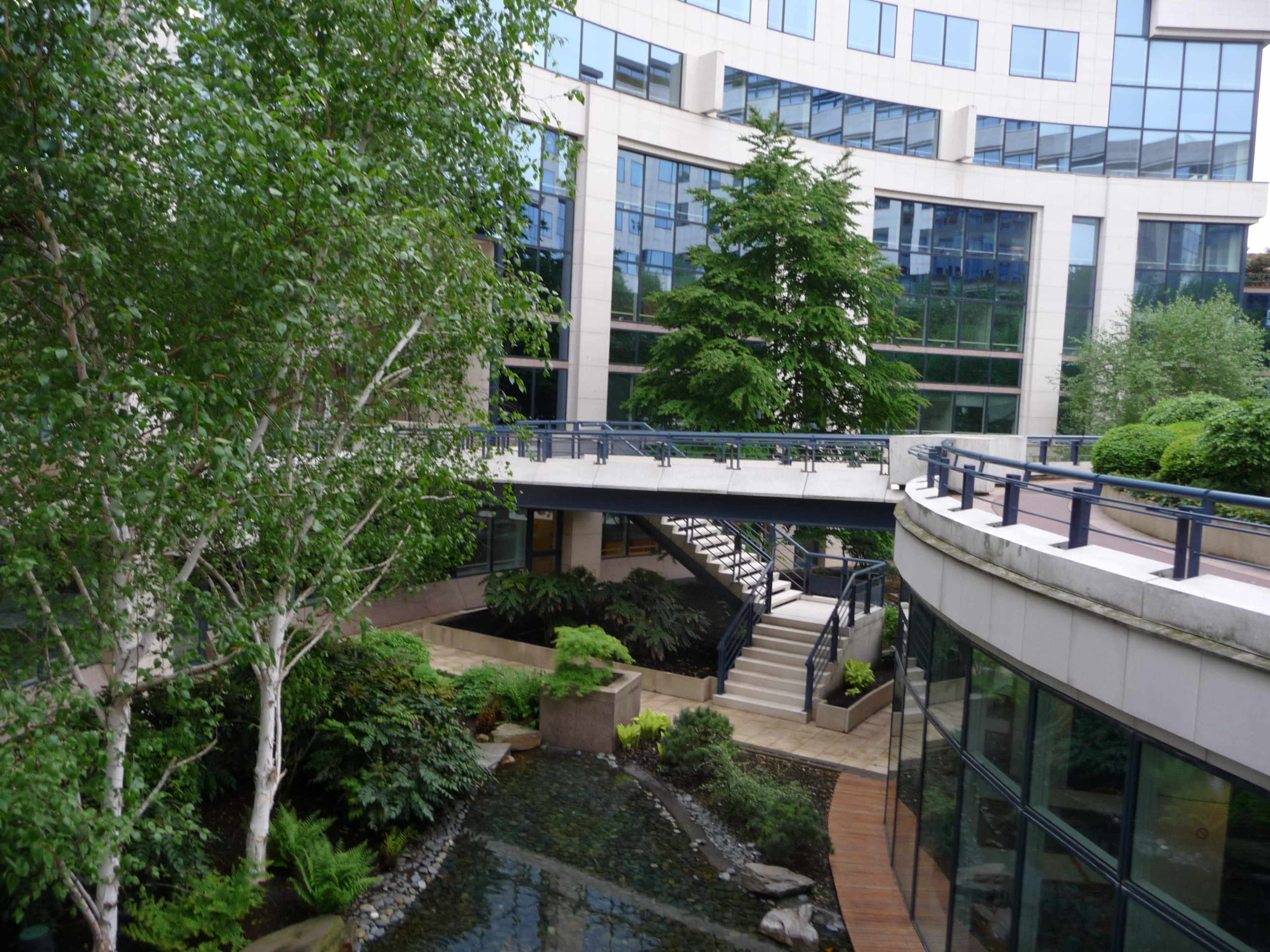 A landscaped courtyard with a water feature, surrounded by modern buildings and greenery.