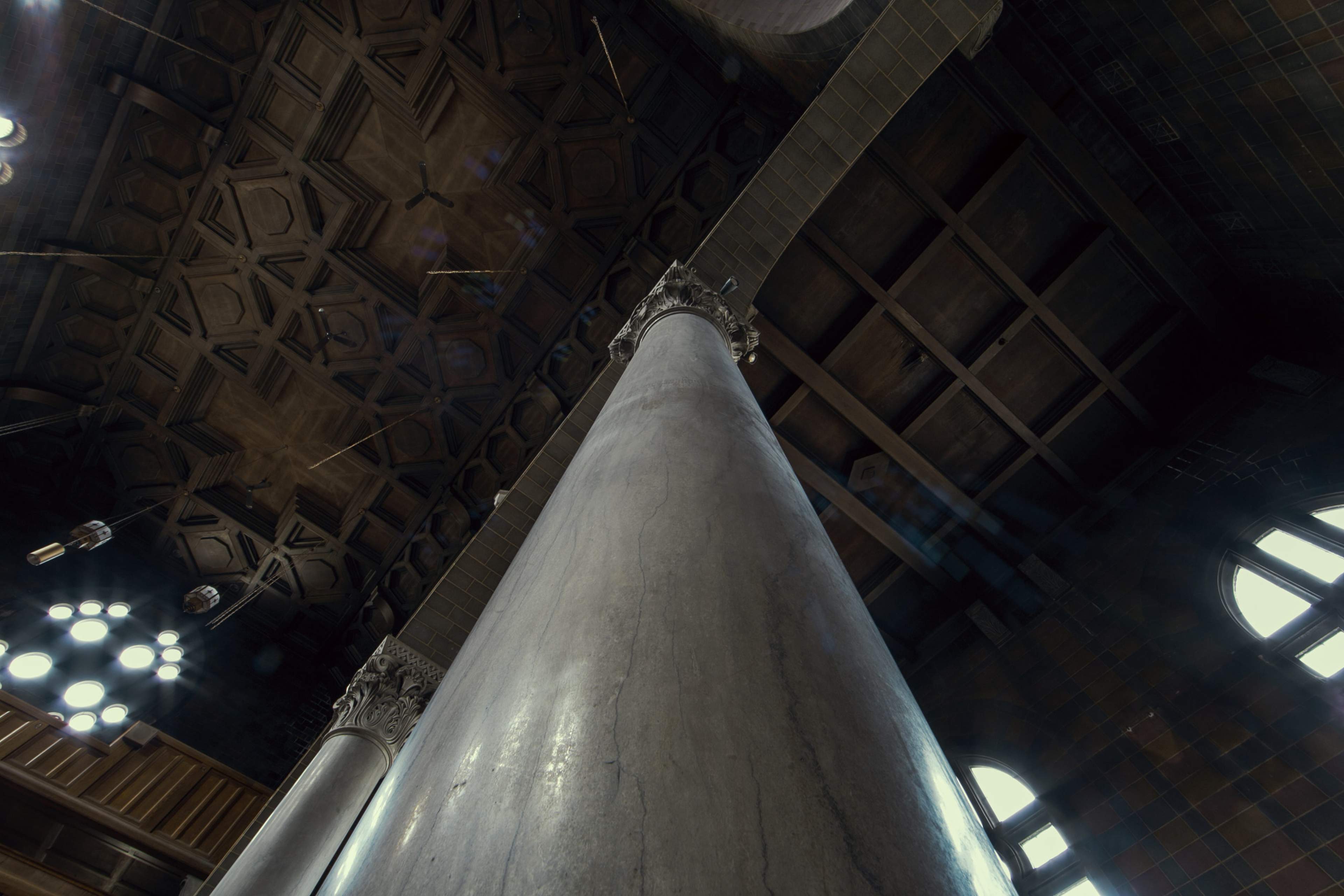 A view looking up at a tall column and an intricately designed ceiling in a historic building.