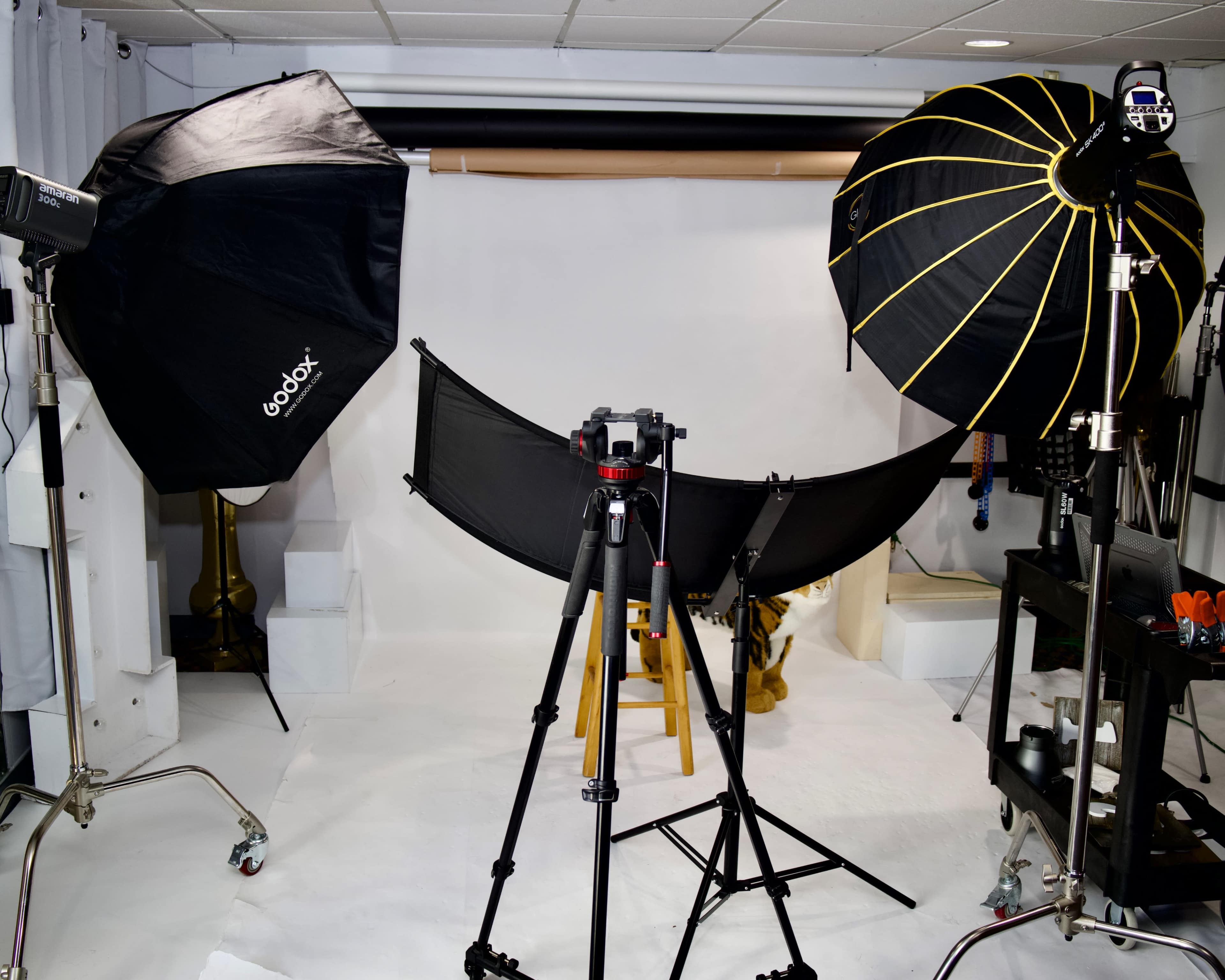 A photography studio setup with two softbox lights, a tripod with a camera, and a backdrop arranged for a photo shoot.