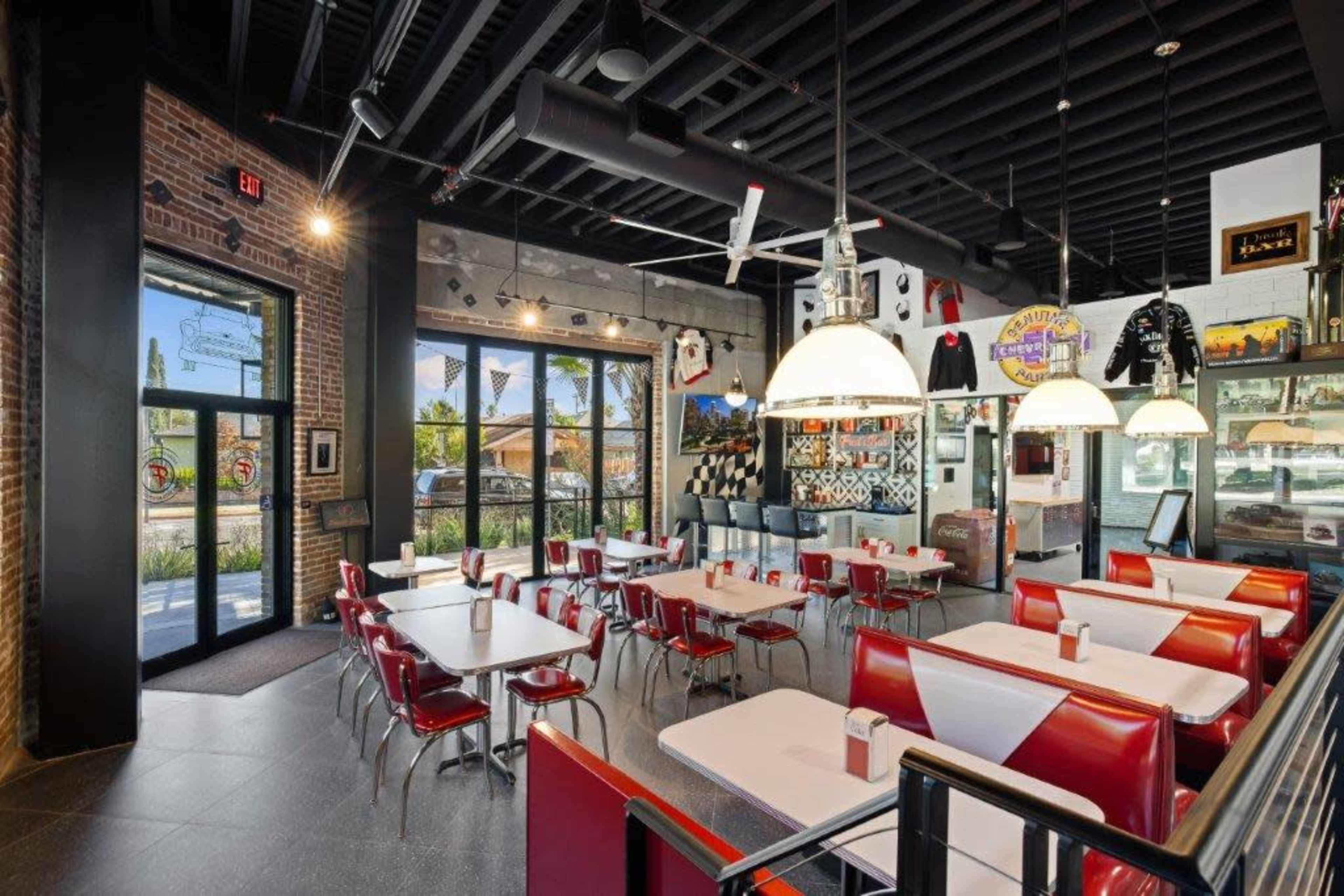 A modern diner interior with red and white seating, large windows, and retro decor.