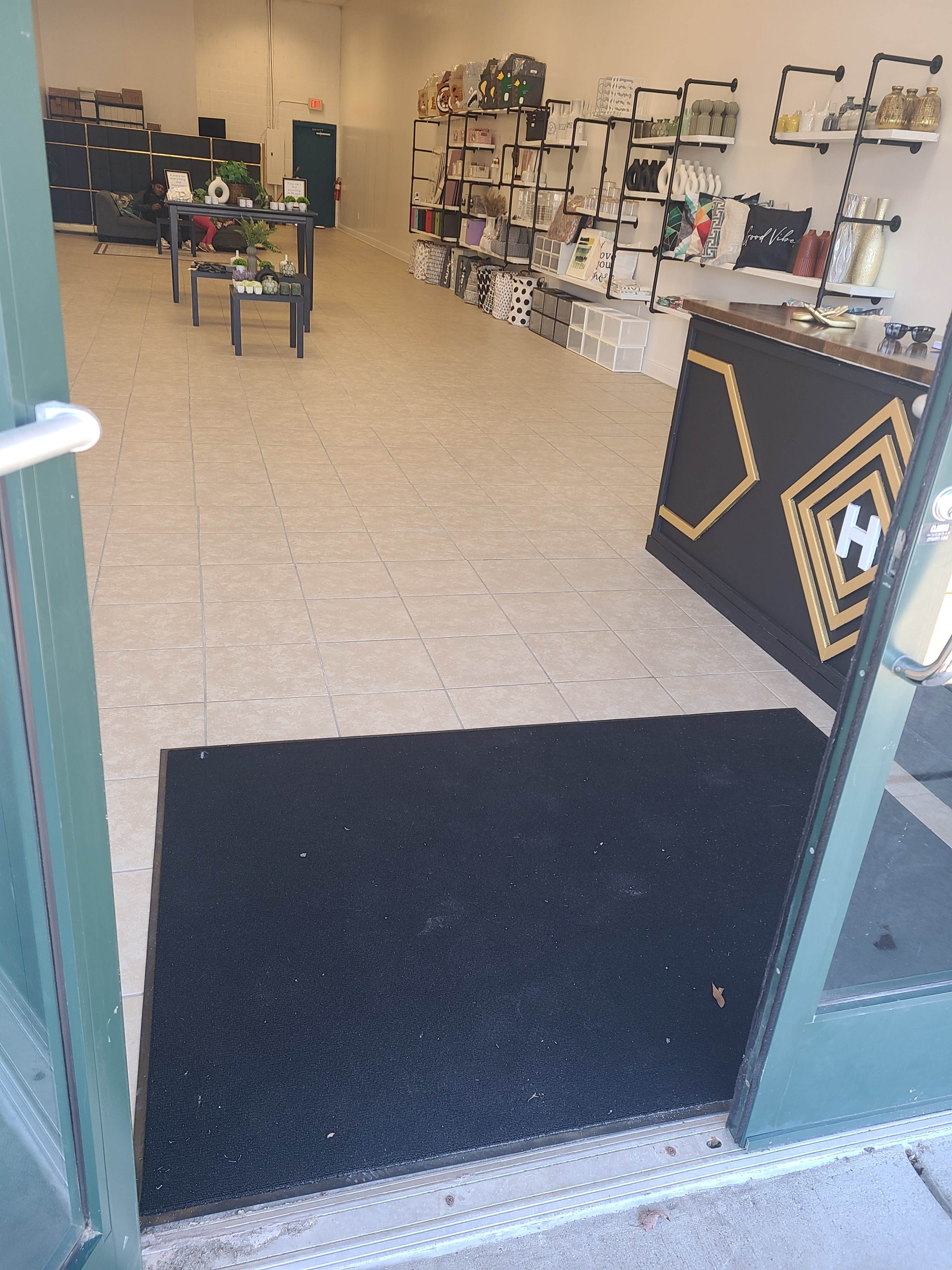 The interior of a retail space, featuring tiled floors, shelves with various items, and a counter near the entrance.