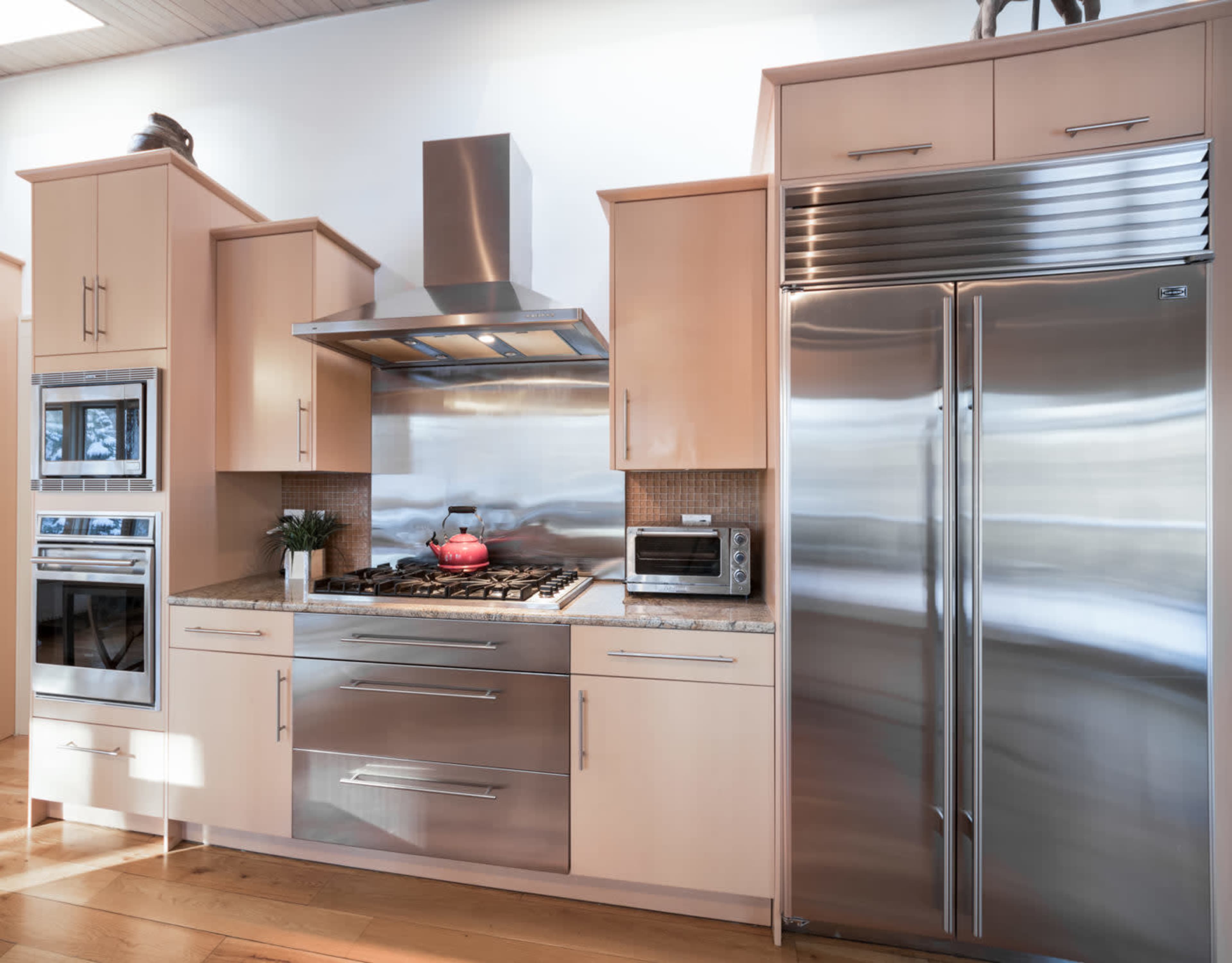 A modern kitchen with stainless steel appliances, wooden cabinetry, and a granite countertop.