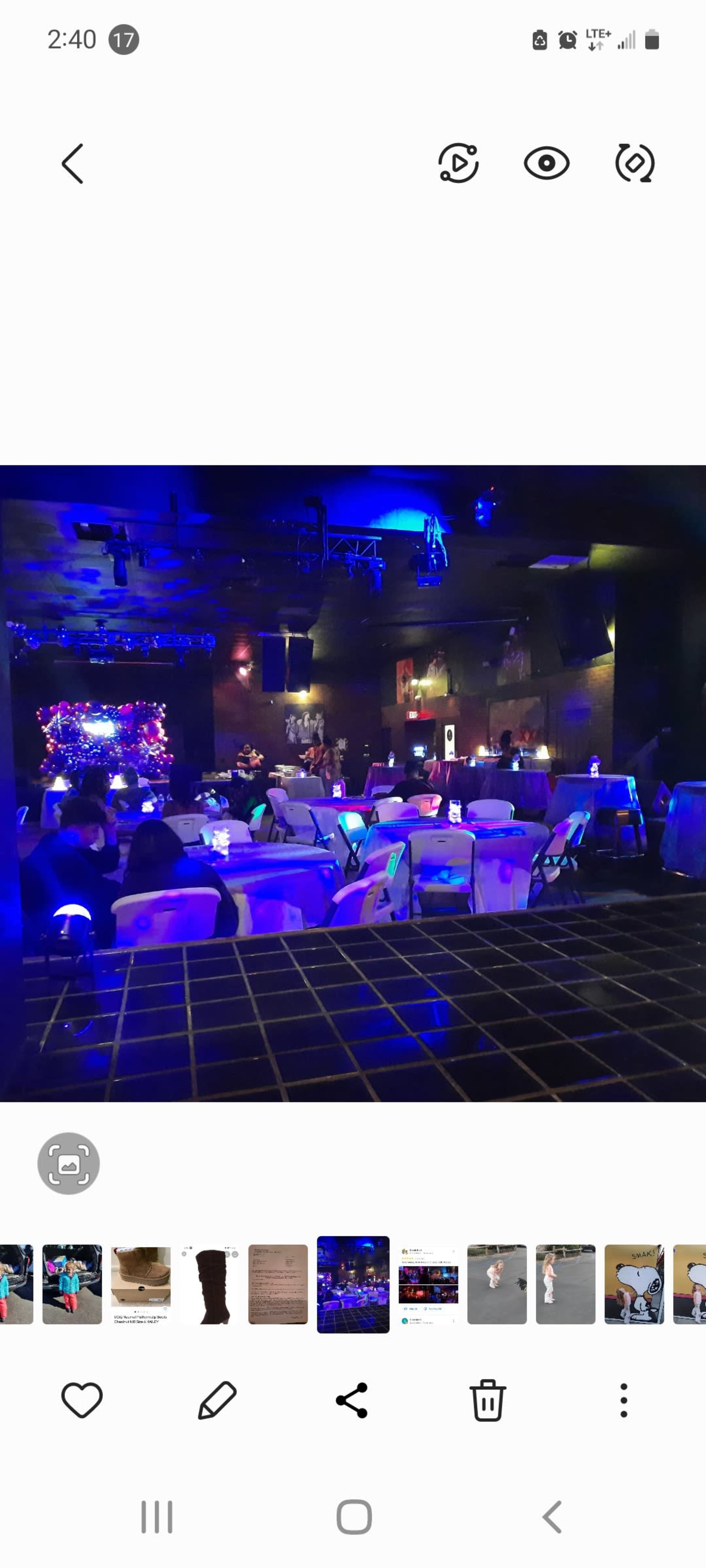 A dimly lit venue with rows of chairs facing a stage adorned with blue and purple lights.