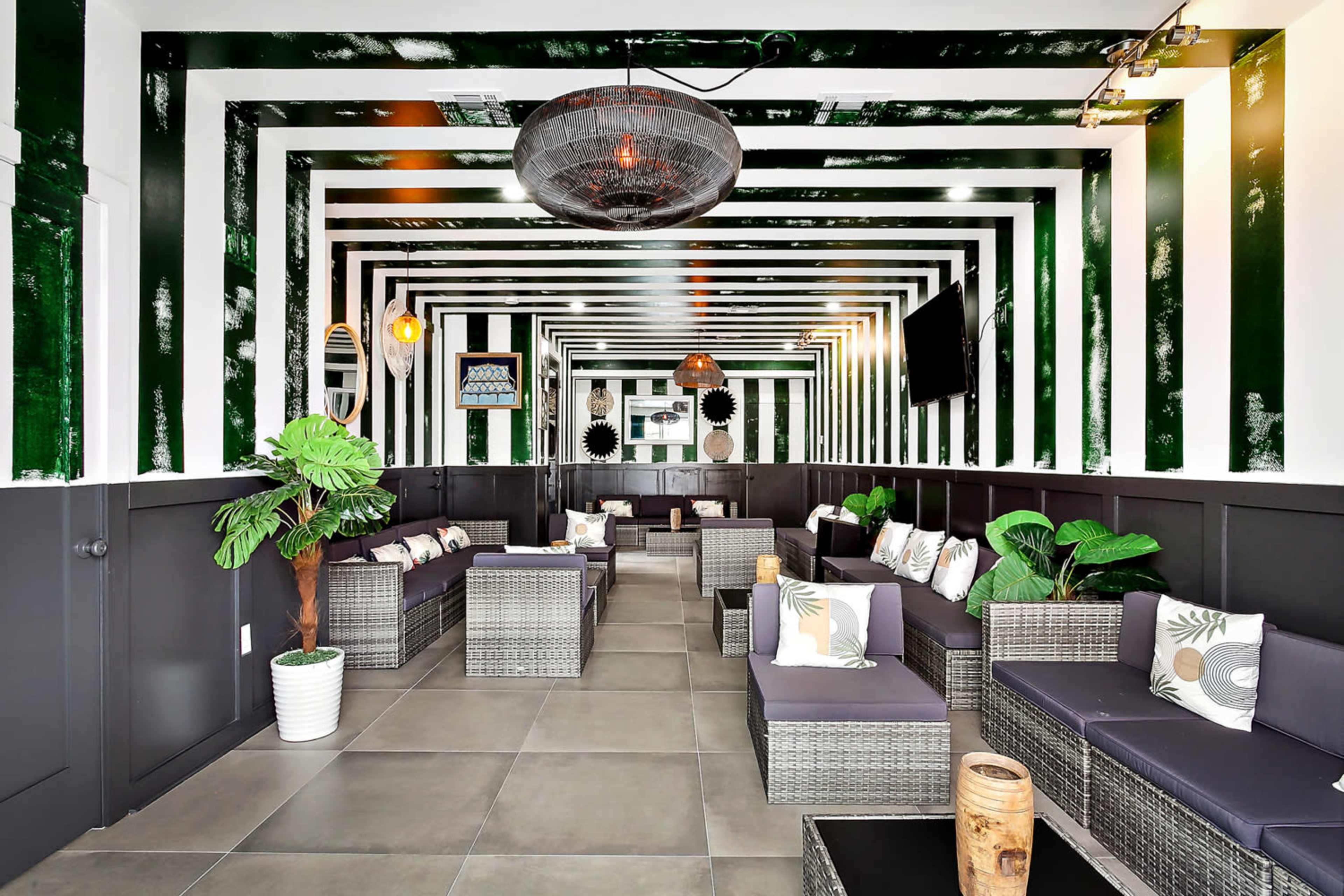 A stylish lounge area featuring modern wicker furniture arranged in a room with bold green and white striped walls.