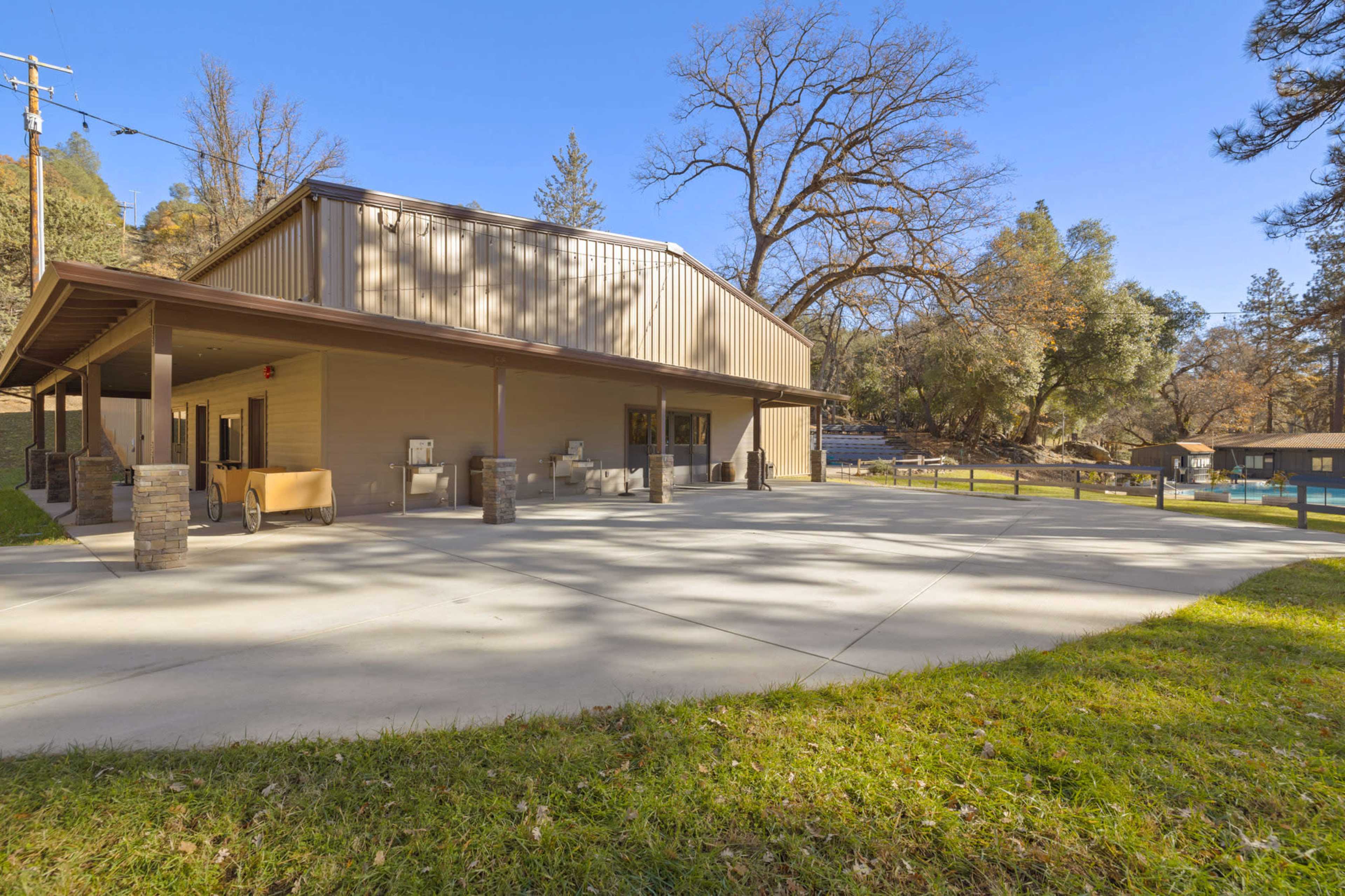 A large, modern building with an outdoor patio area surrounded by trees and a grassy lawn.
