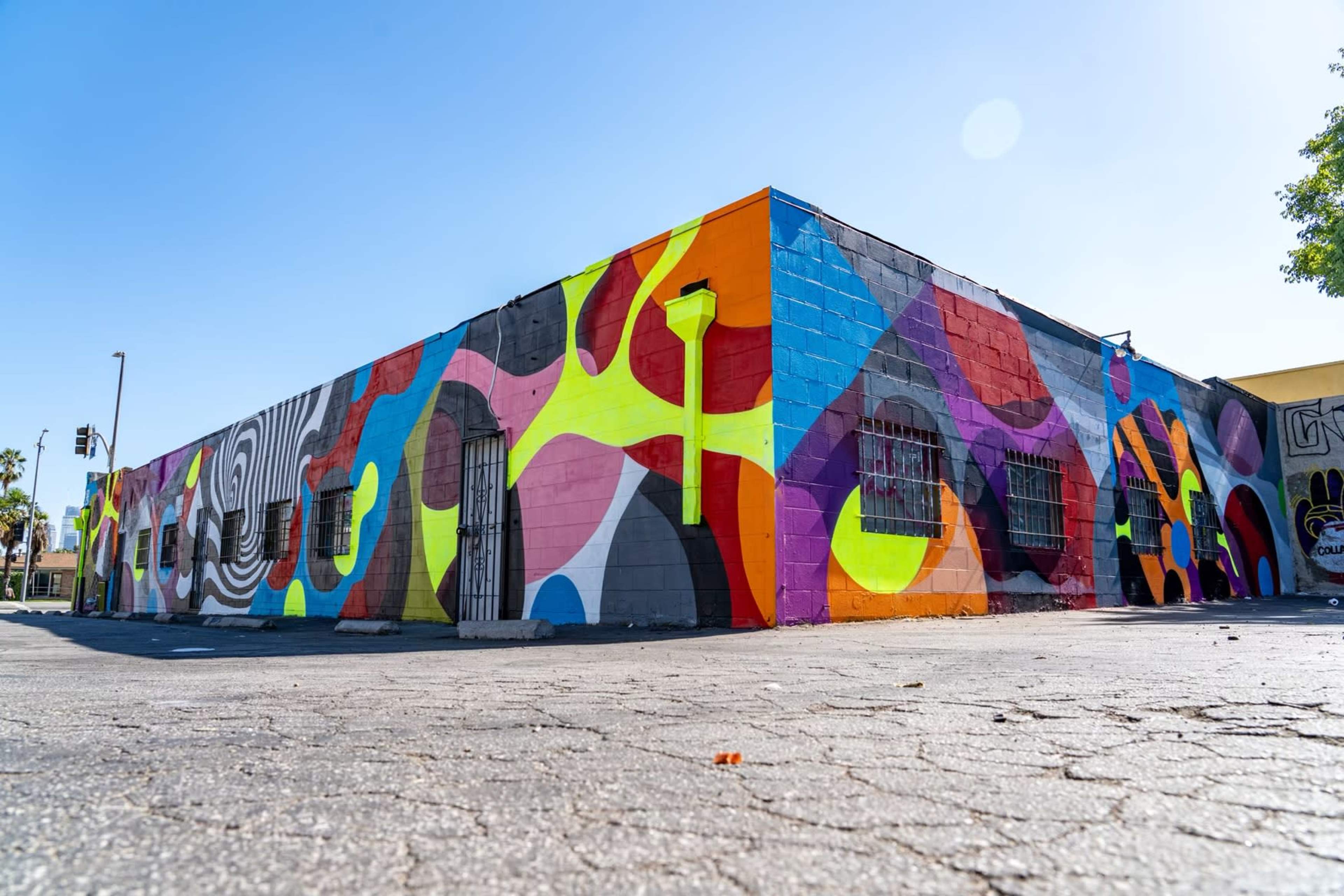 A vibrant, multicolored mural covering the exterior walls of a building in an outdoor urban area.