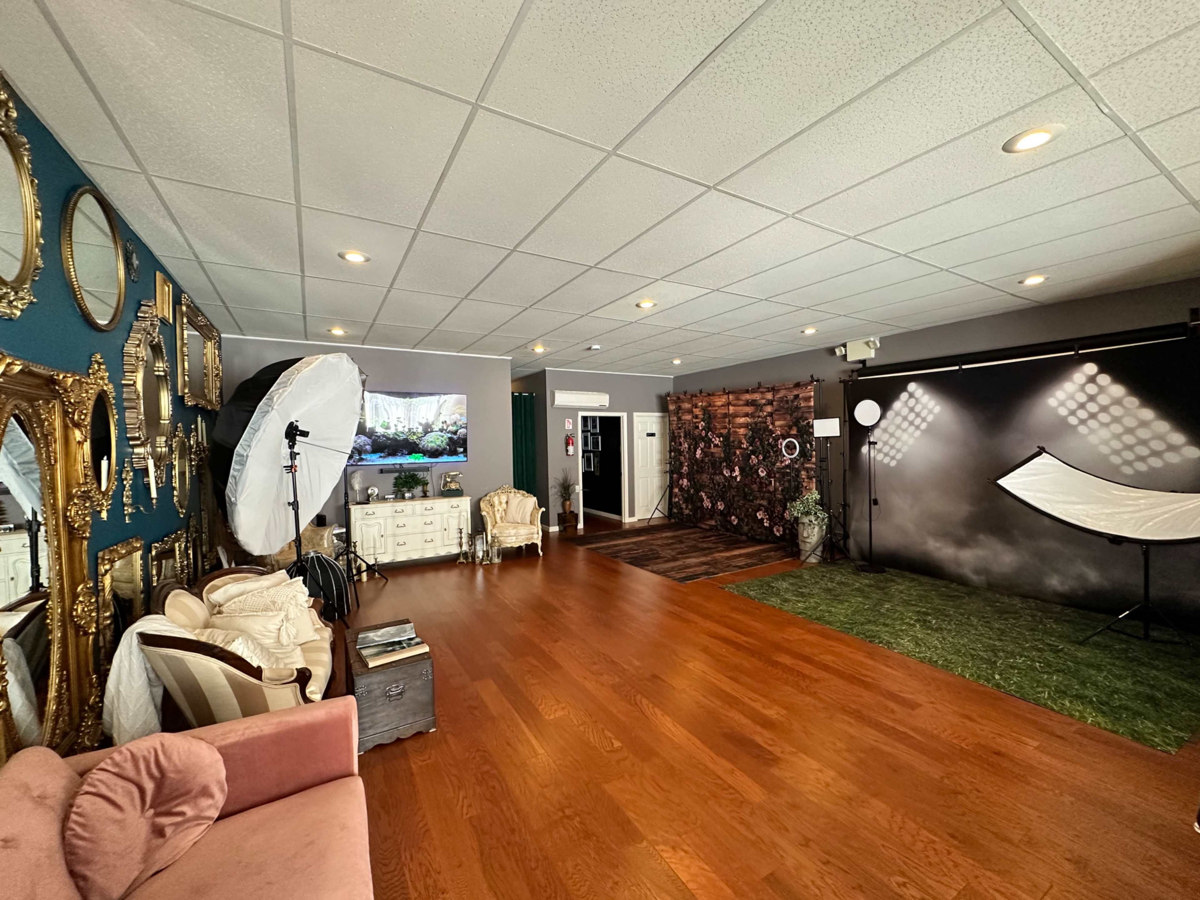 A spacious, well-lit photography studio with decorative mirrors, a variety of backdrops, and equipment set up for photo shoots.