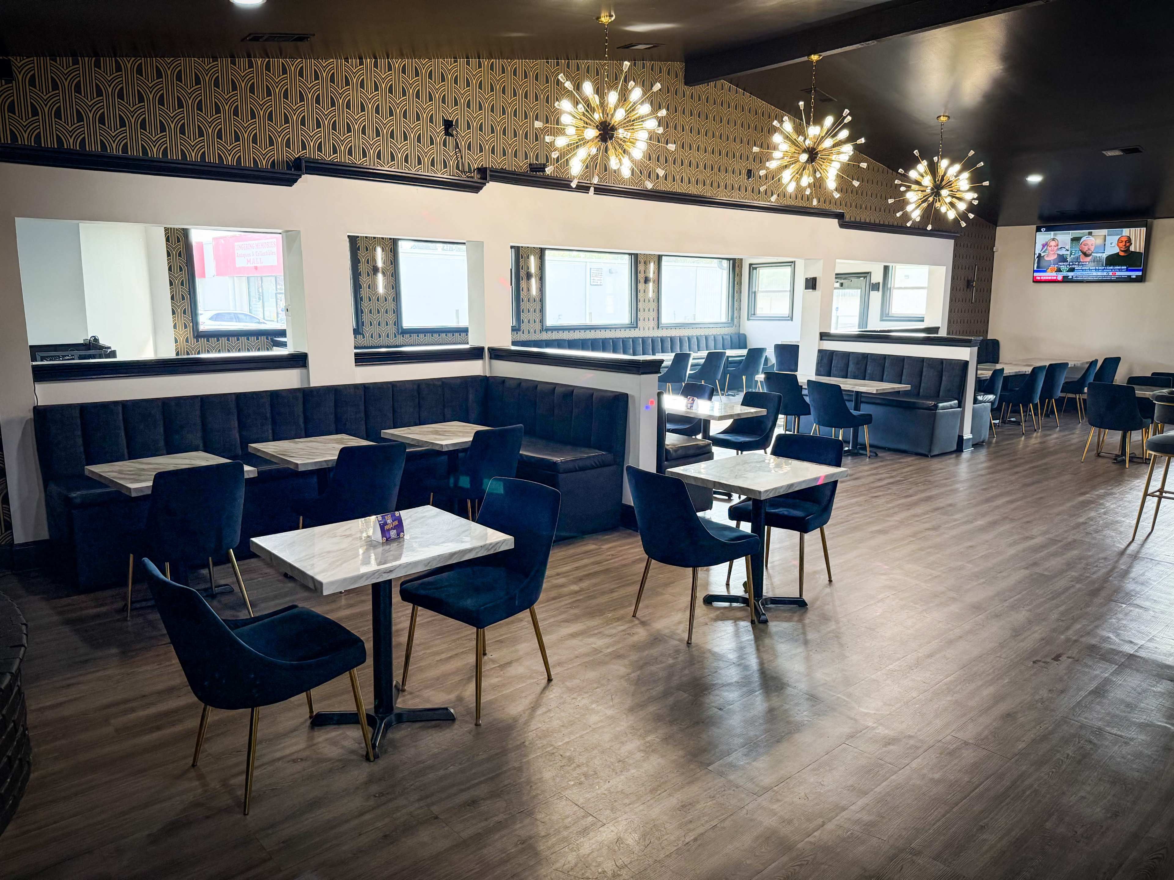The image shows a modern restaurant interior featuring dark blue upholstered seating, marble-topped tables, and decorative lighting fixtures.
