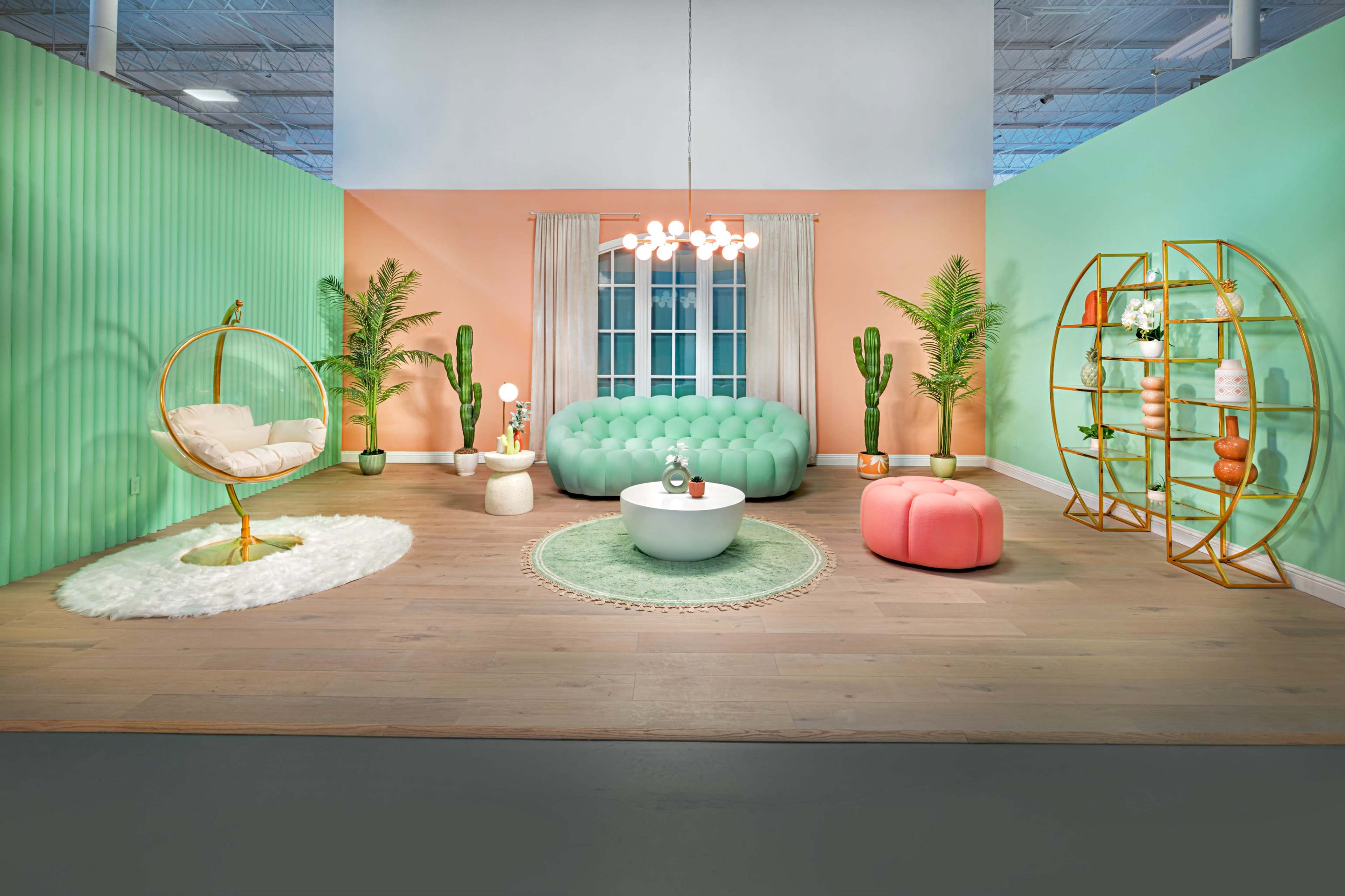 A vibrant living space featuring a green and peach color palette, a tufted green sofa, various plants, and modern furniture.