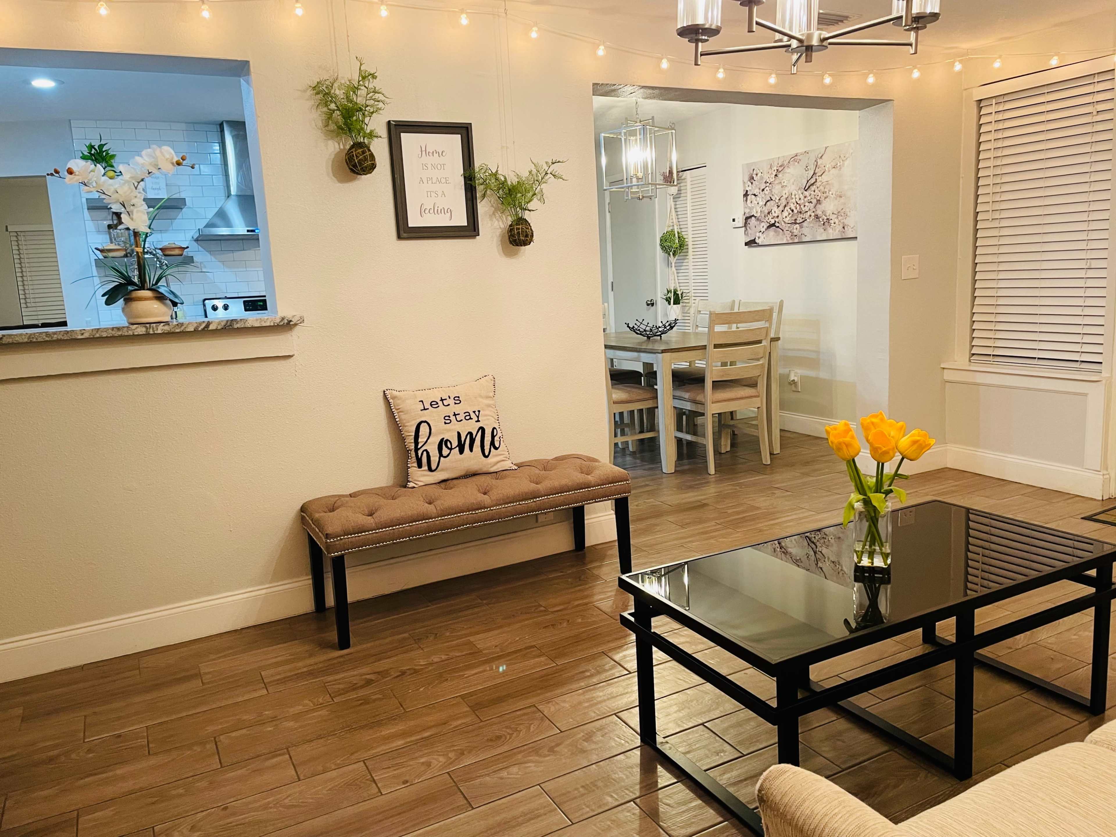 A living room with a bench and a coffee table, surrounded by flowers and decorative lighting.