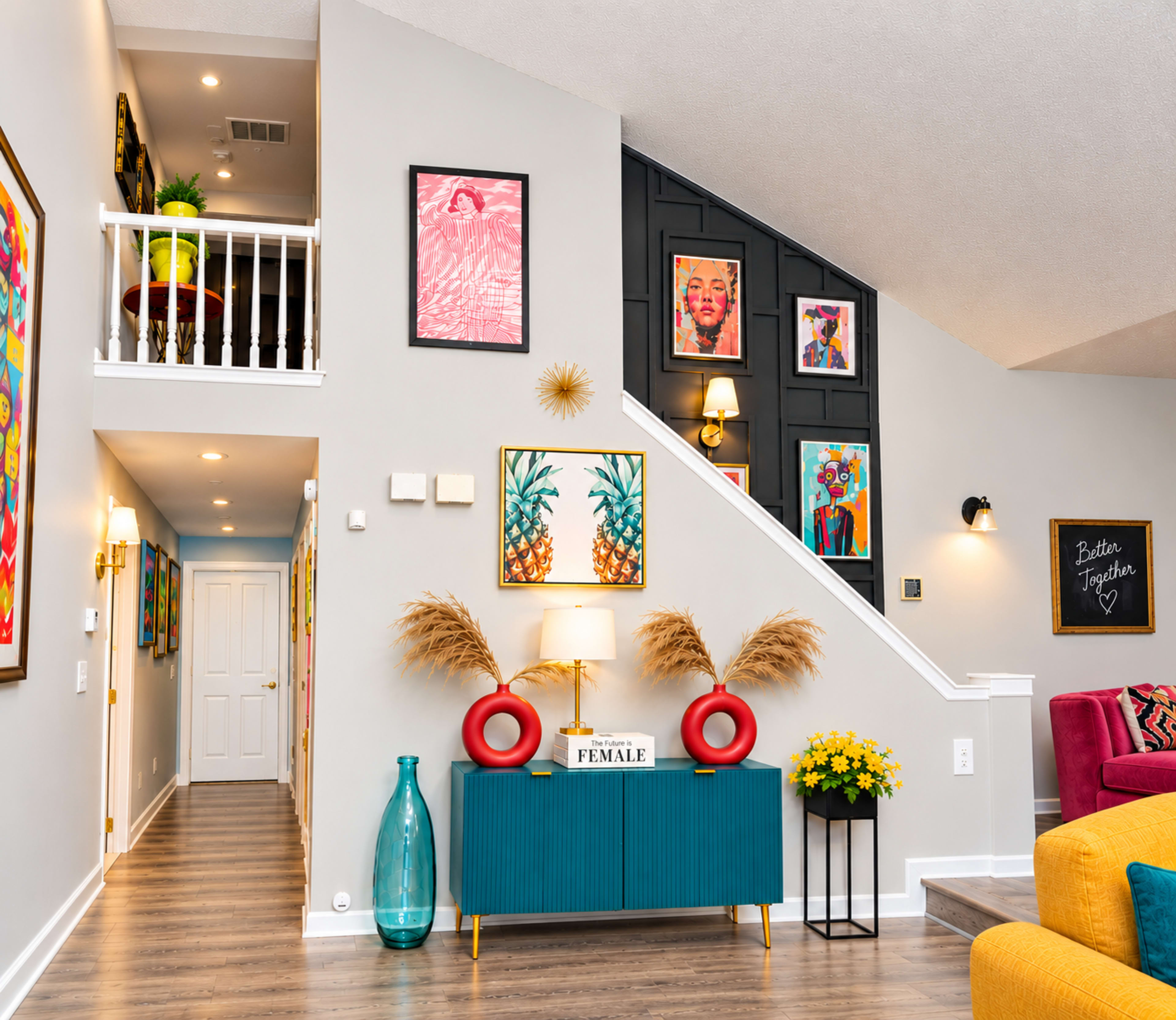 The image shows a brightly decorated hallway with colorful artwork on the walls, a teal cabinet with a lamp and decor, and a staircase leading to an upper level.