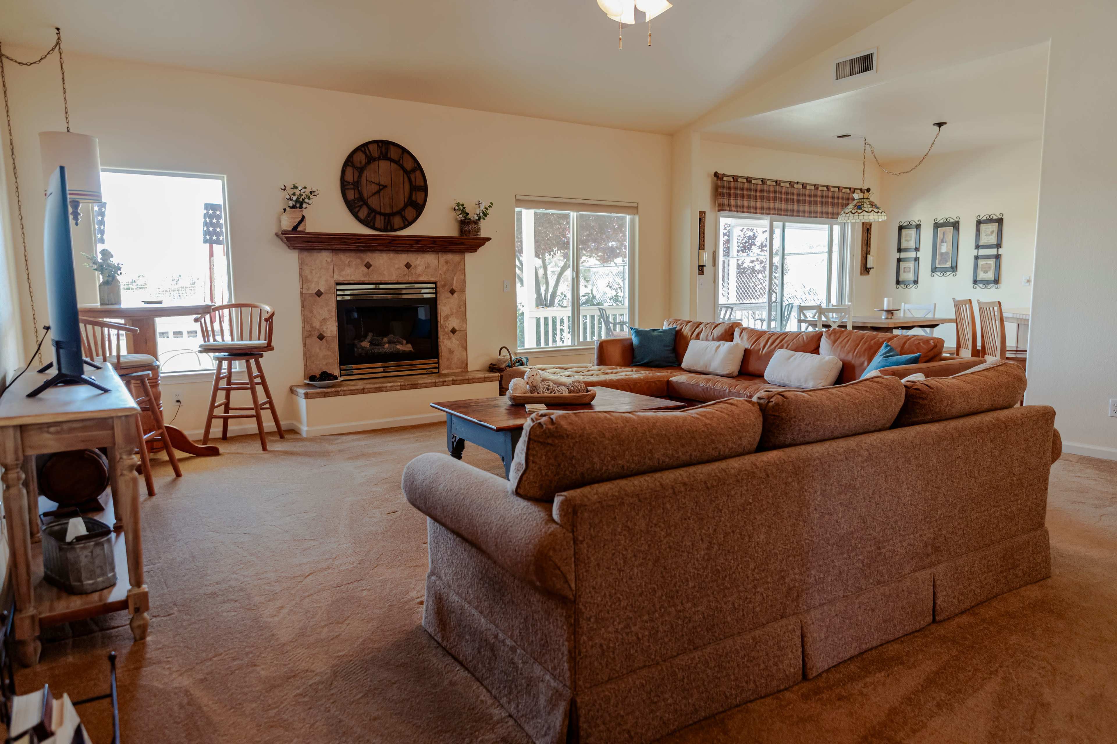 A spacious living room with a large sectional sofa, a fireplace, and windows providing natural light.