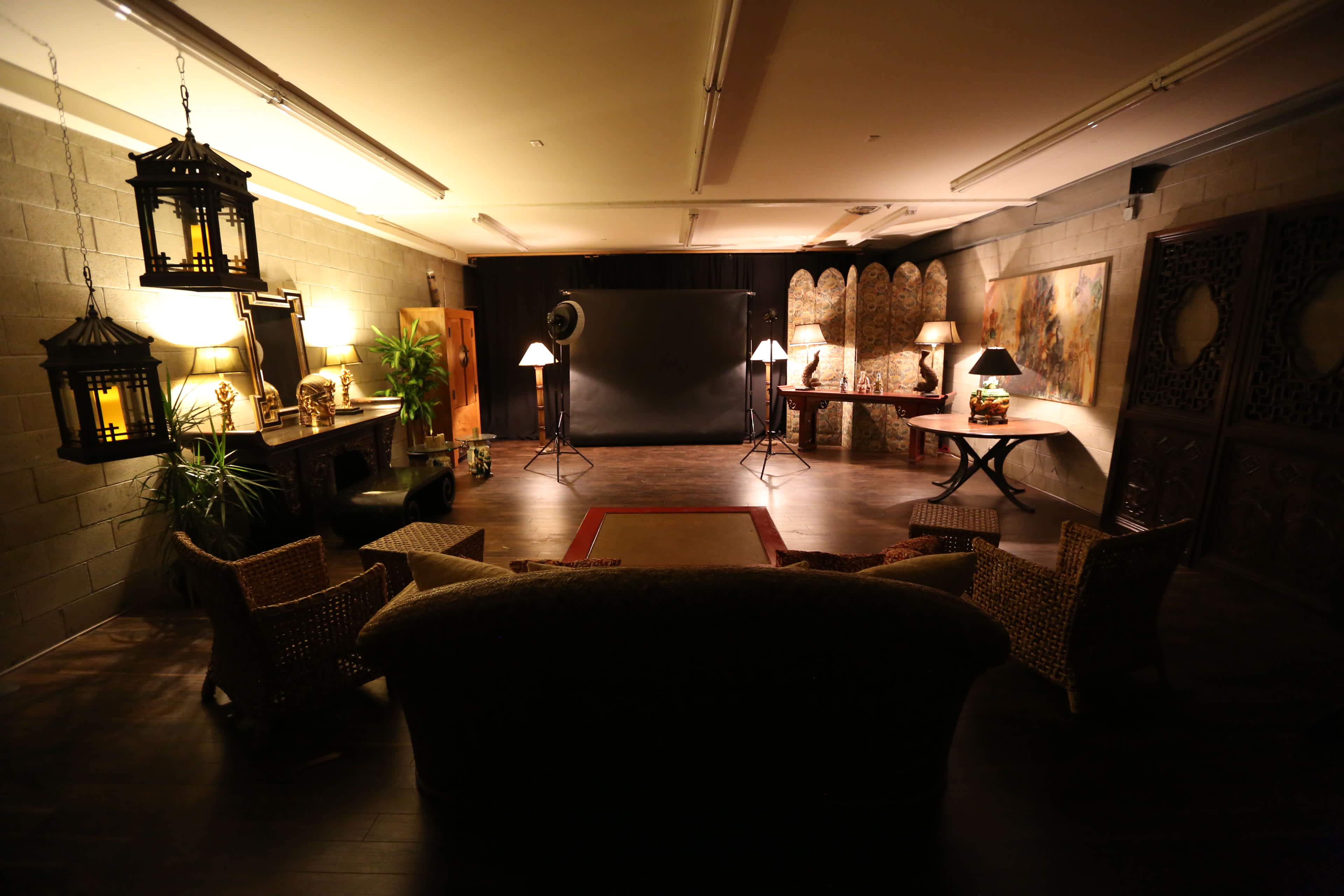 A spacious, well-decorated studio with a dark floor, various lighting fixtures, and seating arrangements surrounded by decorative walls.