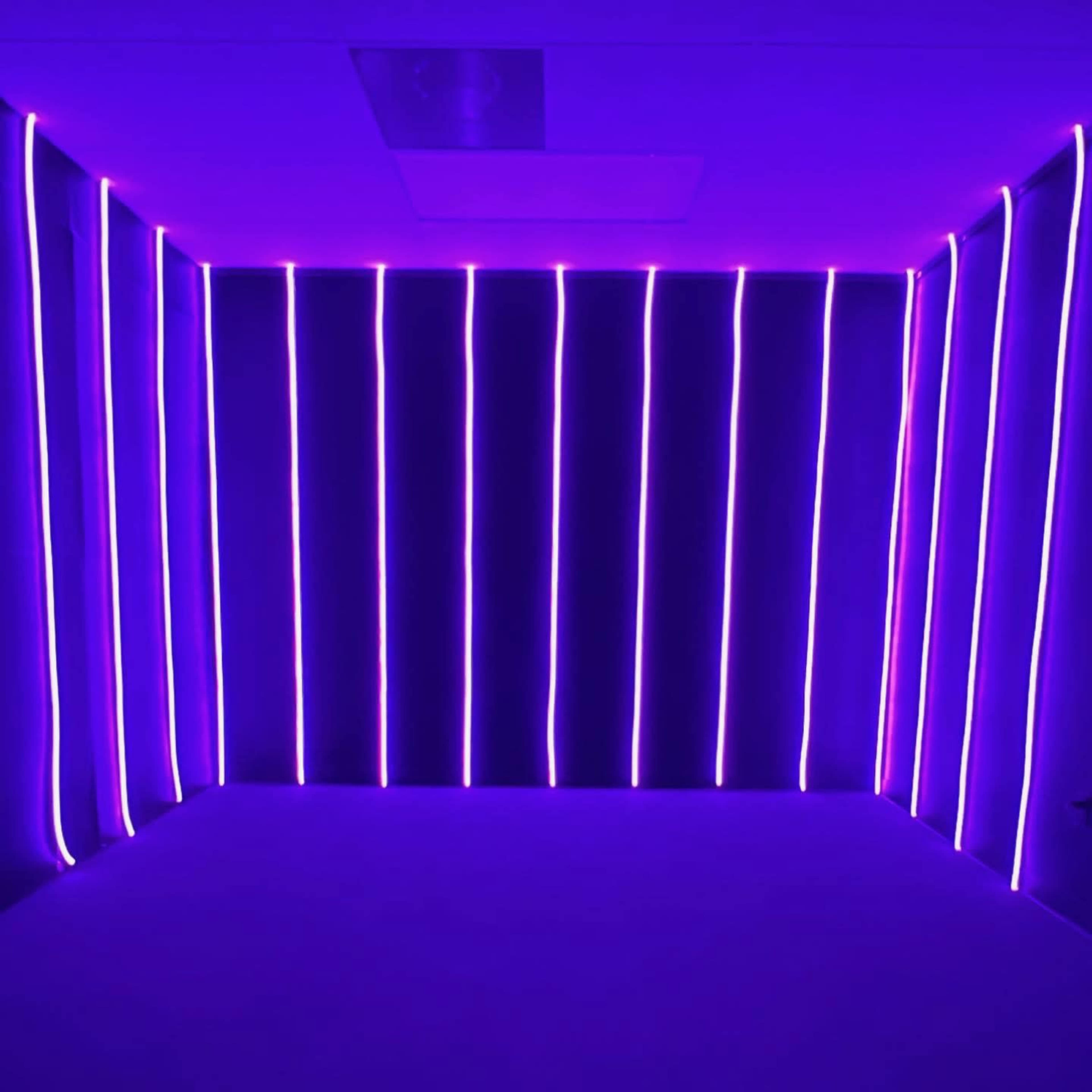 The image shows an empty room with purple neon lights arranged vertically along the walls.