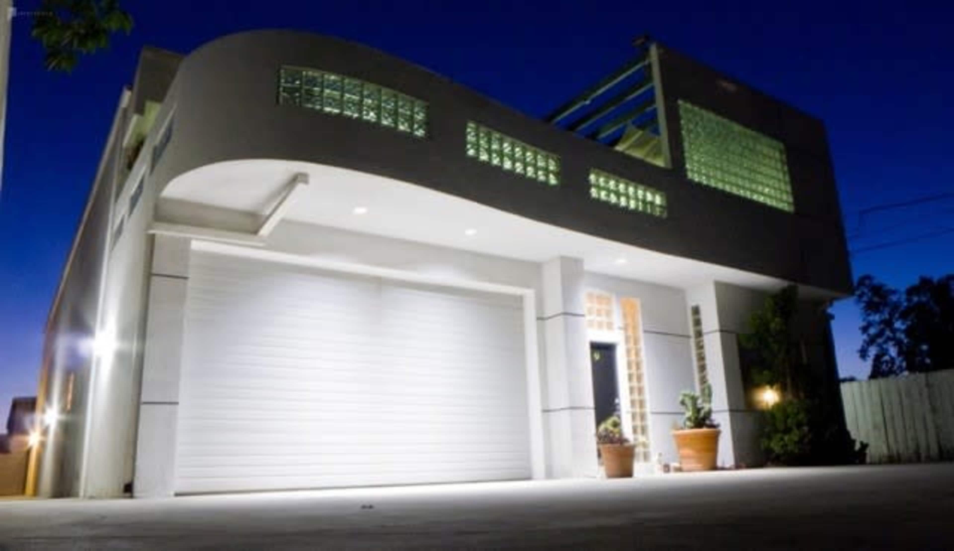 A modern house with a curved roof and glass block windows, illuminated at dusk.