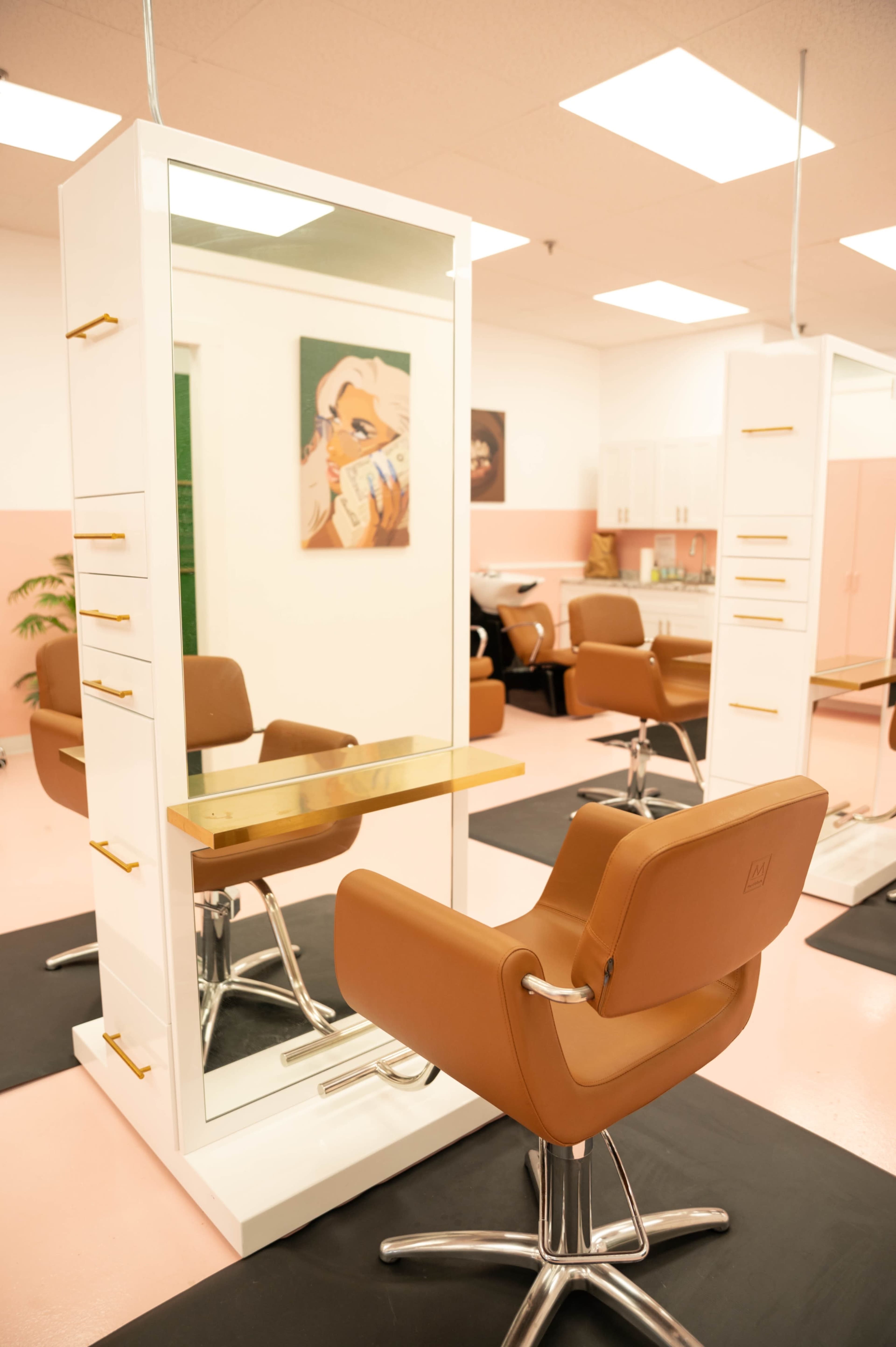 A modern hair salon with stylist stations featuring mirrors, elegant chairs, and a pink and white color scheme.
