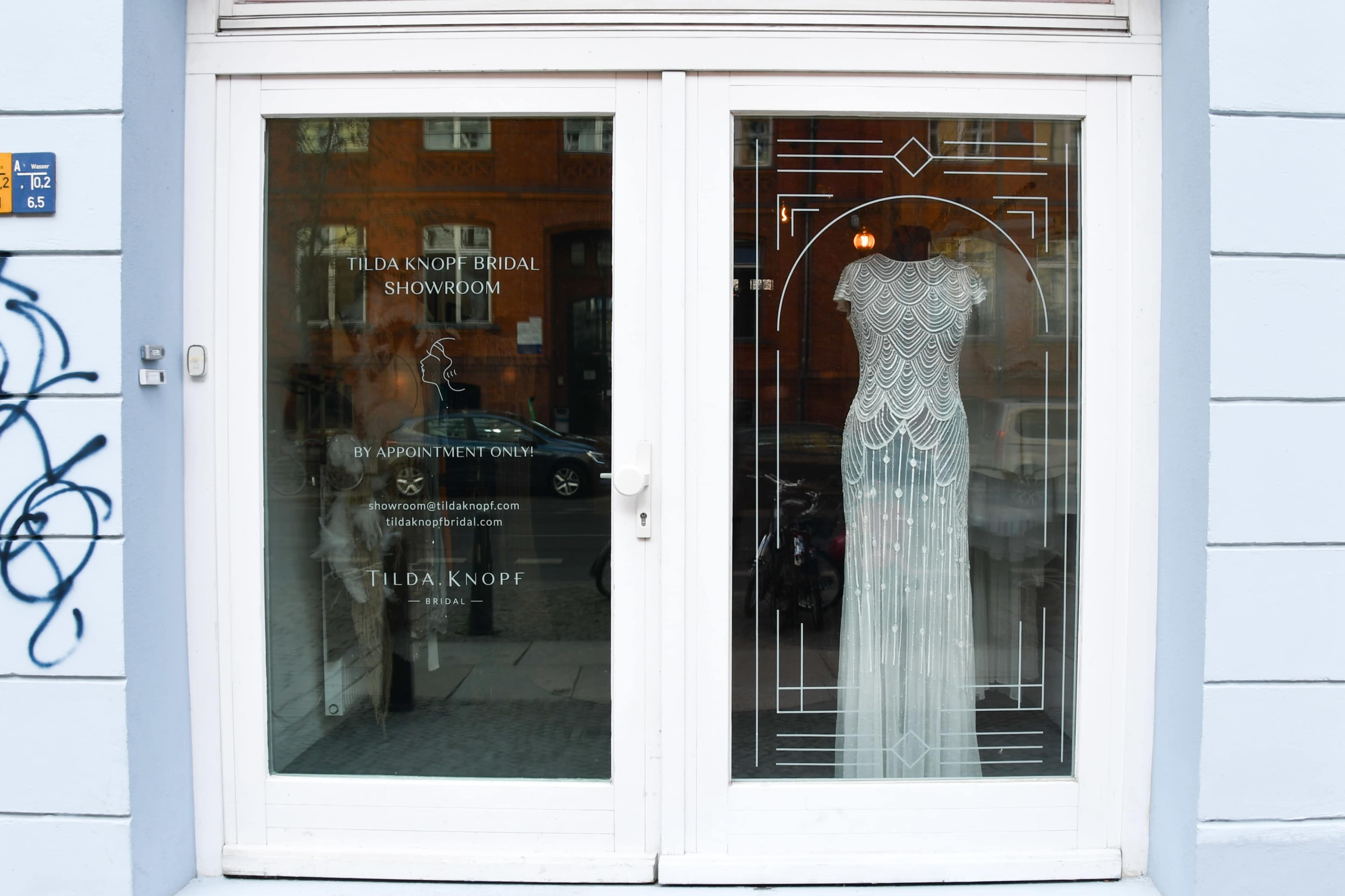 The image shows a glass storefront for "Tilda Knopf Bridal Showroom," featuring a wedding dress displayed behind the glass door.