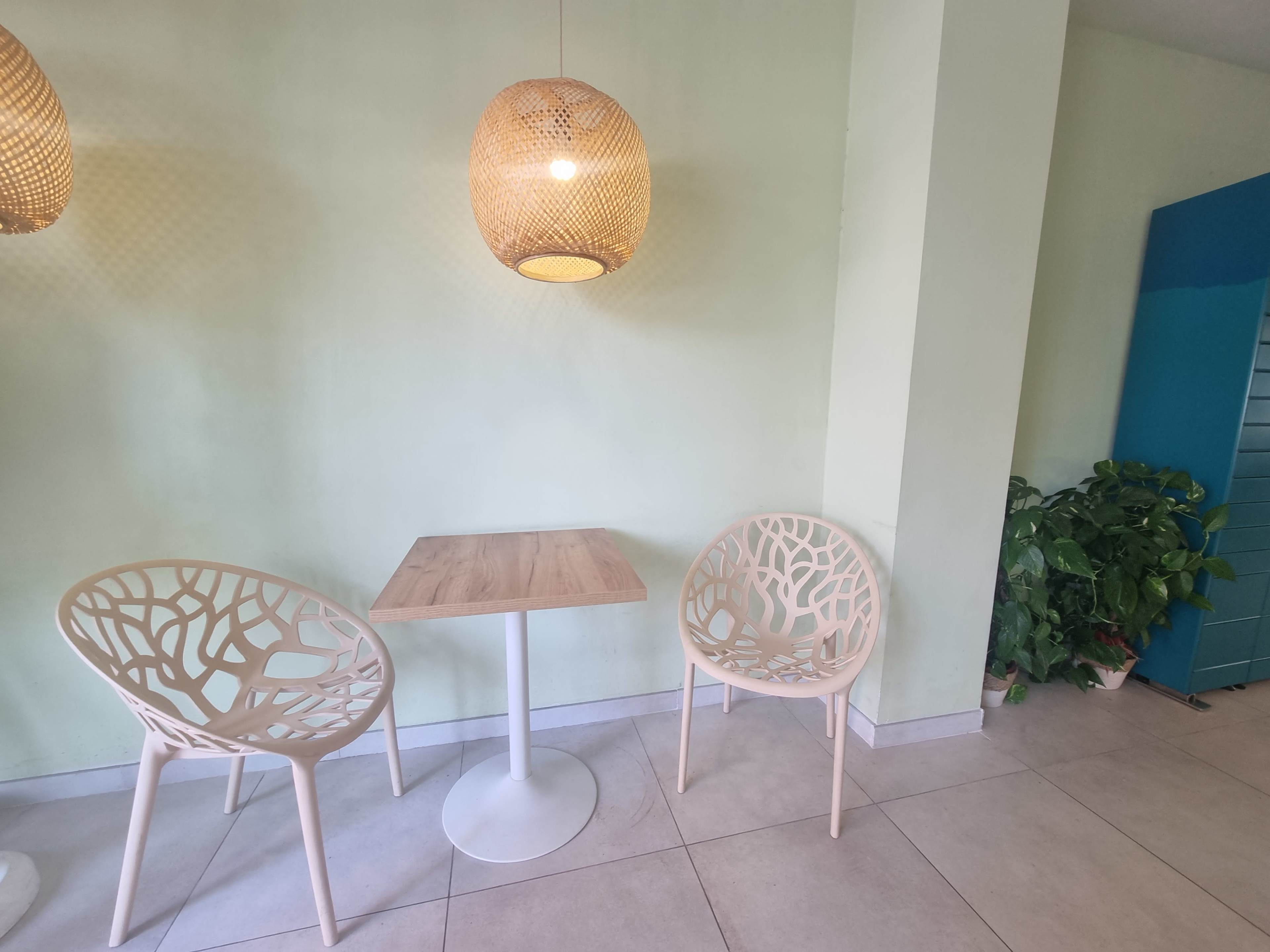 A small seating area features two decorative chairs and a round table against a pale green wall.