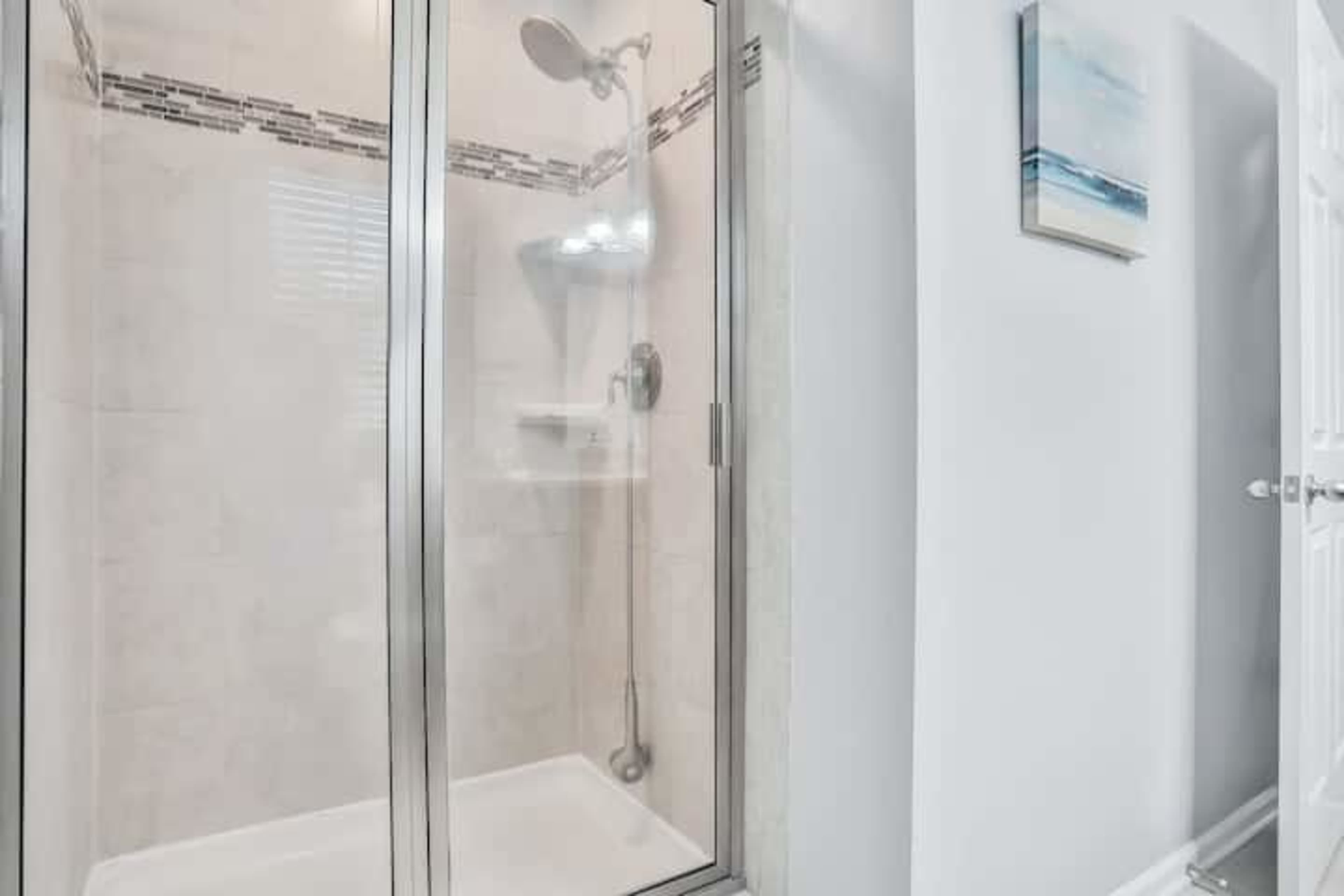 A glass shower enclosure with a showerhead and a tiled wall in a bathroom.