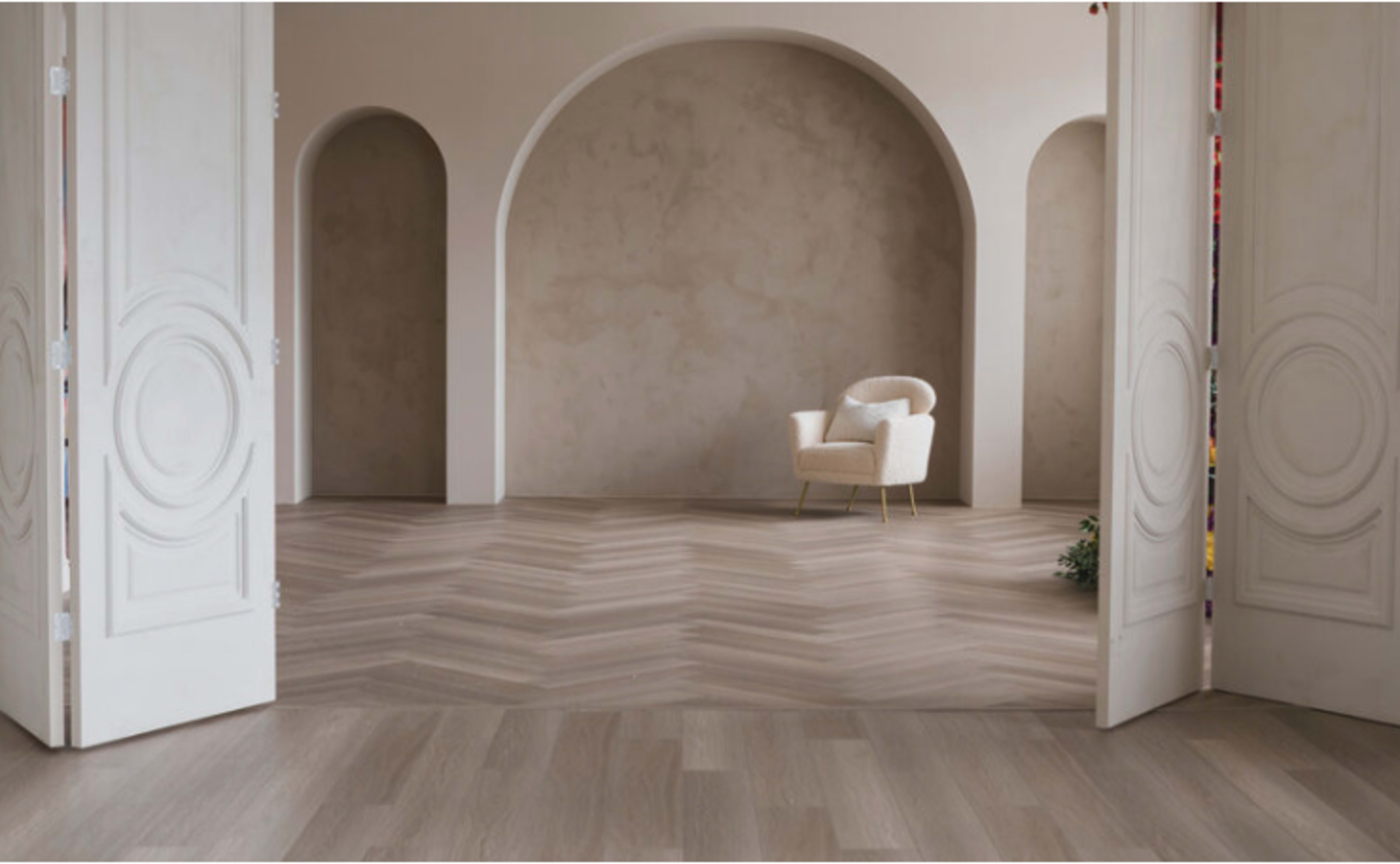 A minimalistic interior space features a chair in front of an arched wall, with herringbone-patterned flooring and double doors framing the scene.