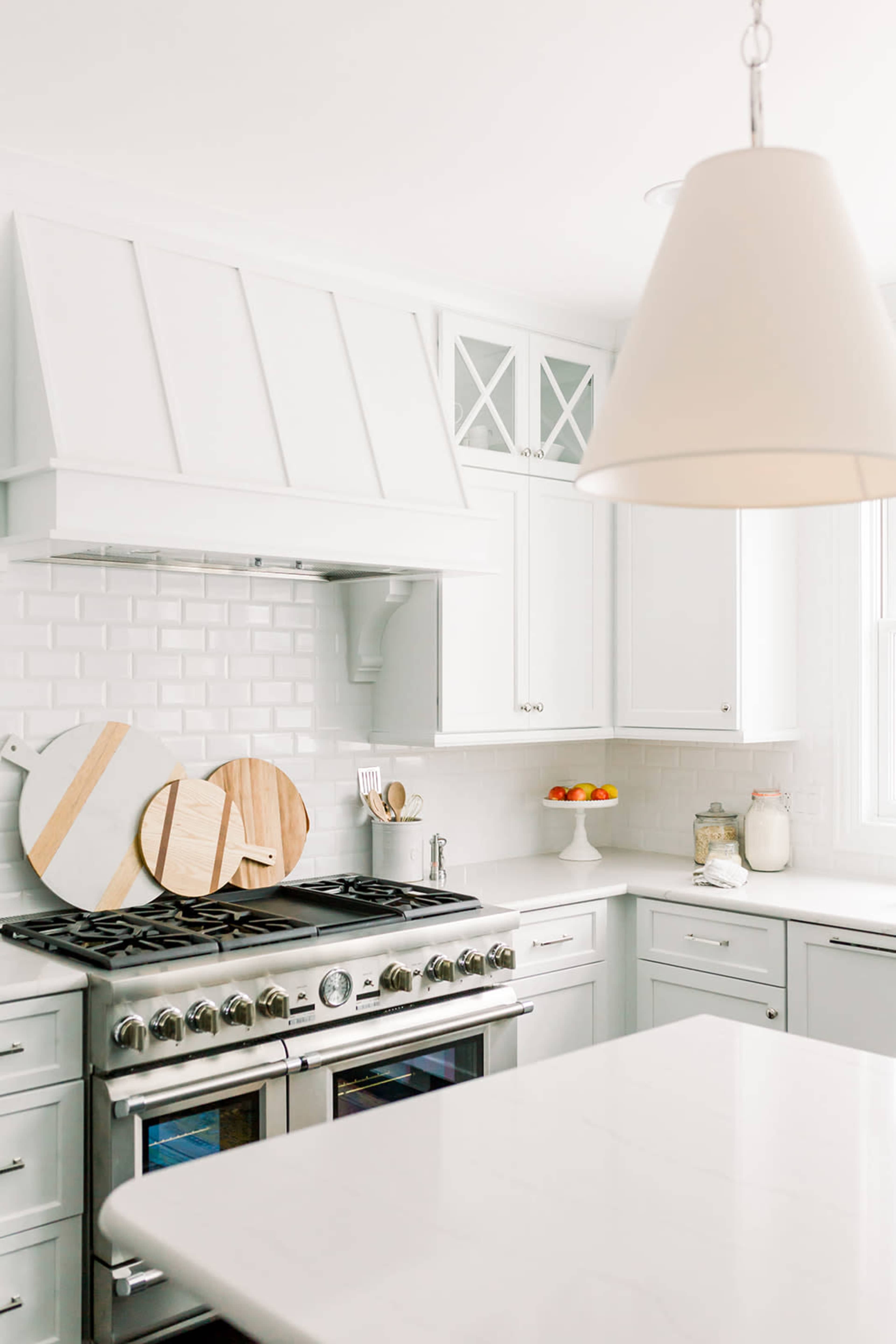 A modern kitchen features white cabinetry, a stainless steel oven, and wooden cutting boards displayed on the countertop.