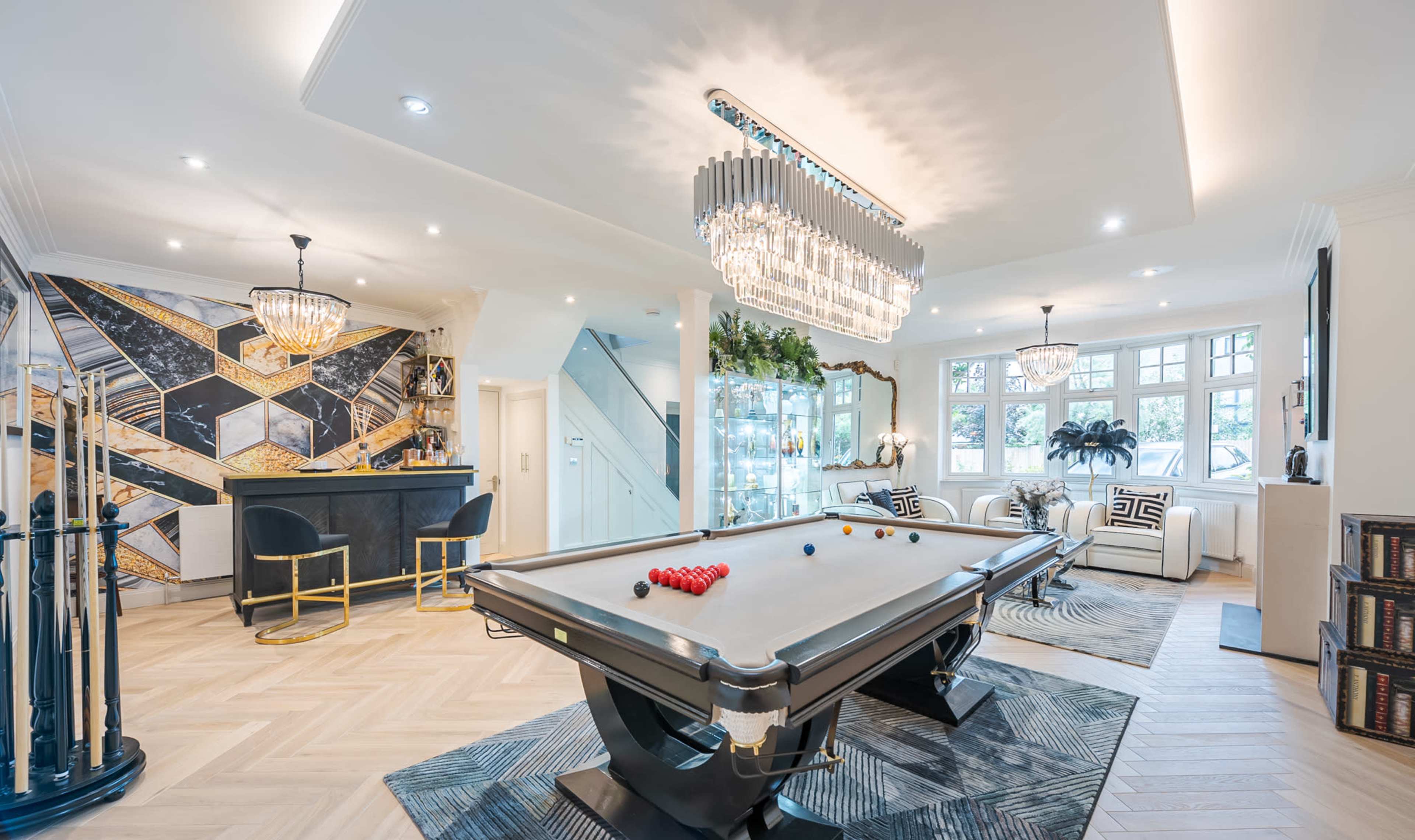 A modern entertainment room featuring a pool table, a bar area, and elegant lighting fixtures.