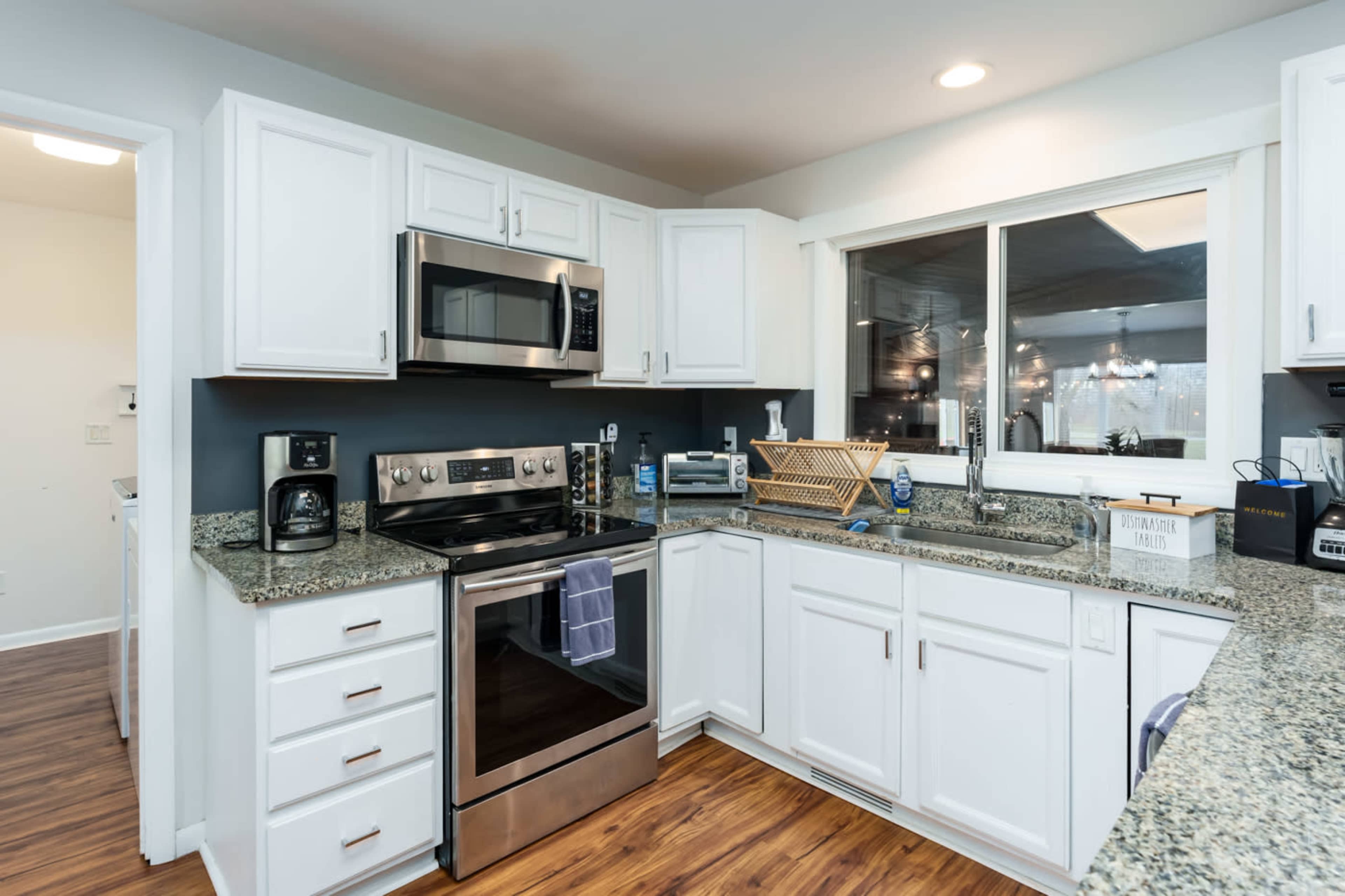 A modern kitchen with white cabinets, stainless steel appliances, and a granite countertop.