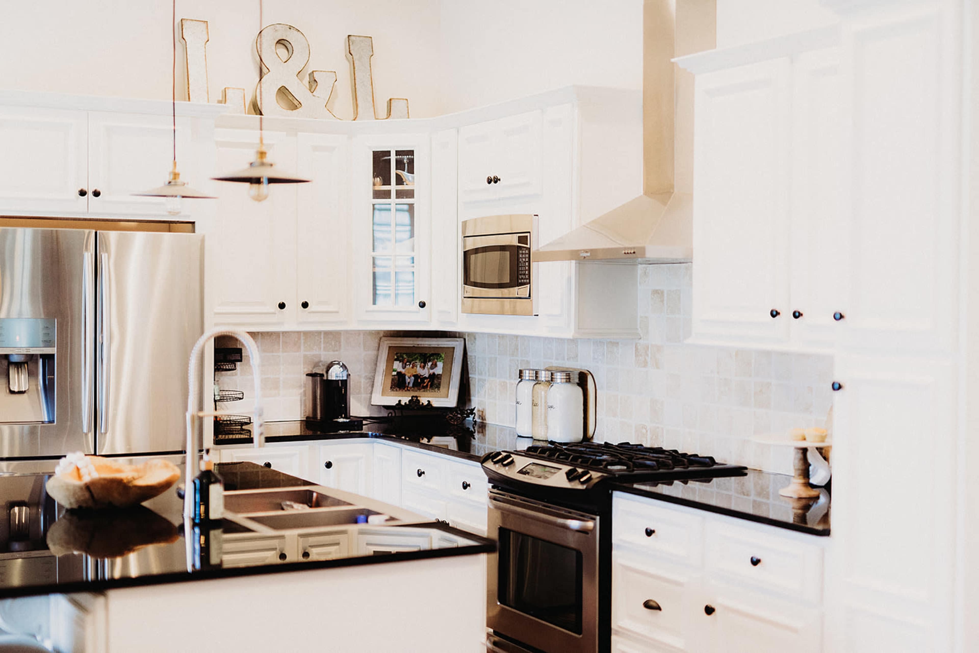 A modern kitchen with white cabinetry, black countertops, and stainless steel appliances.