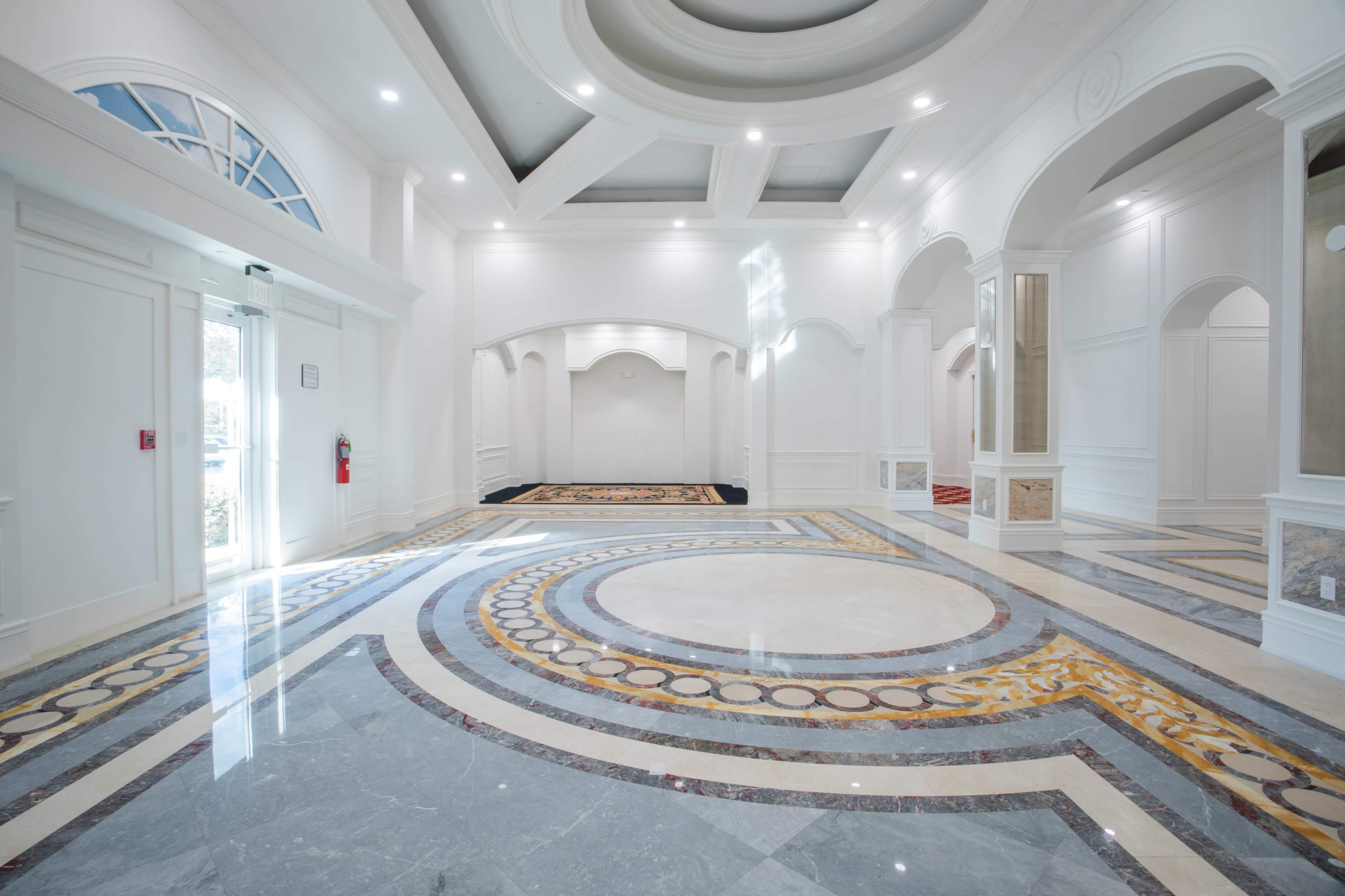 A spacious, well-lit lobby with marble flooring and elegant archways.