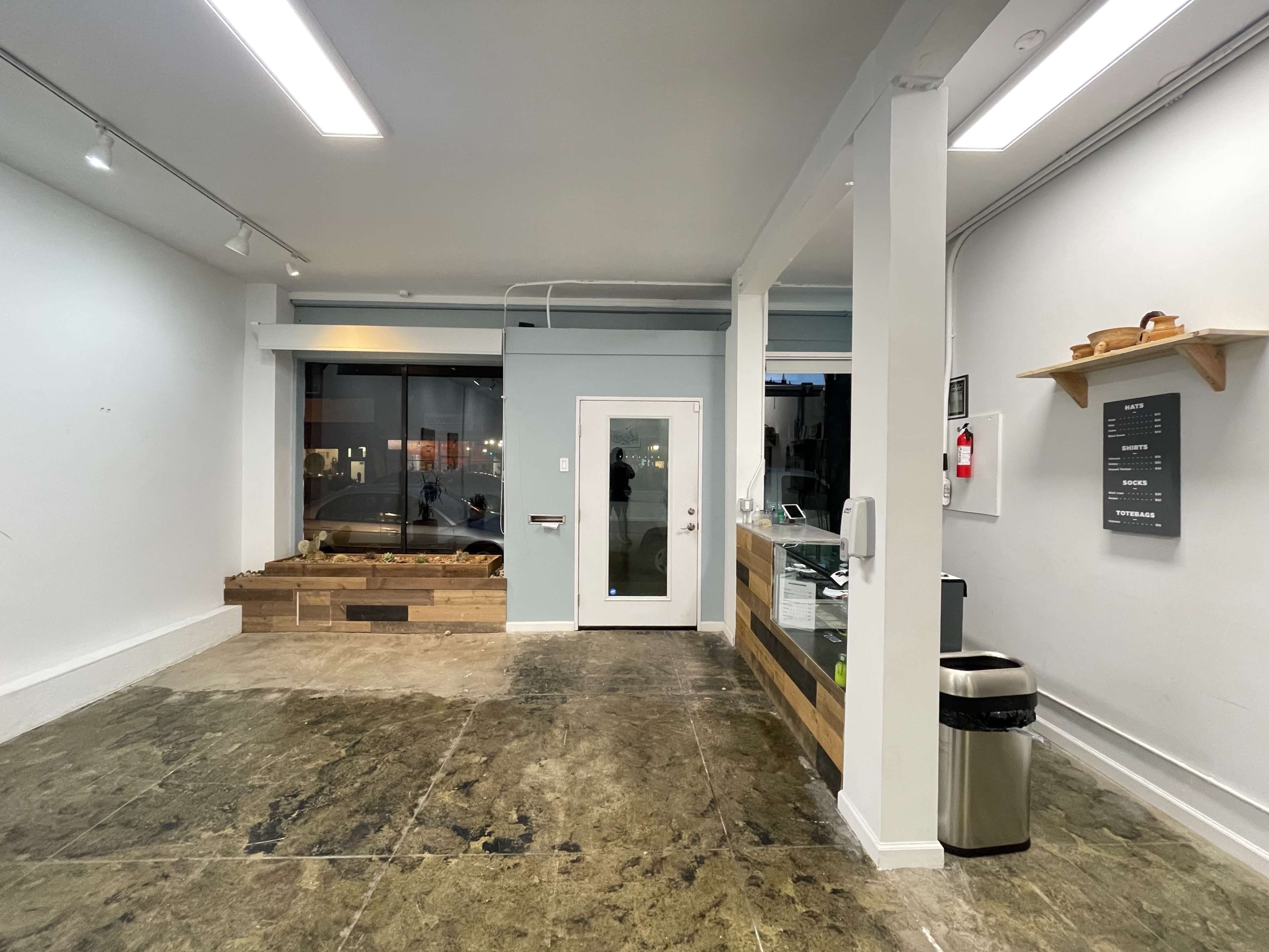 A spacious, minimalistic interior of a commercial space with a reception area, a large window, and a door leading outside.