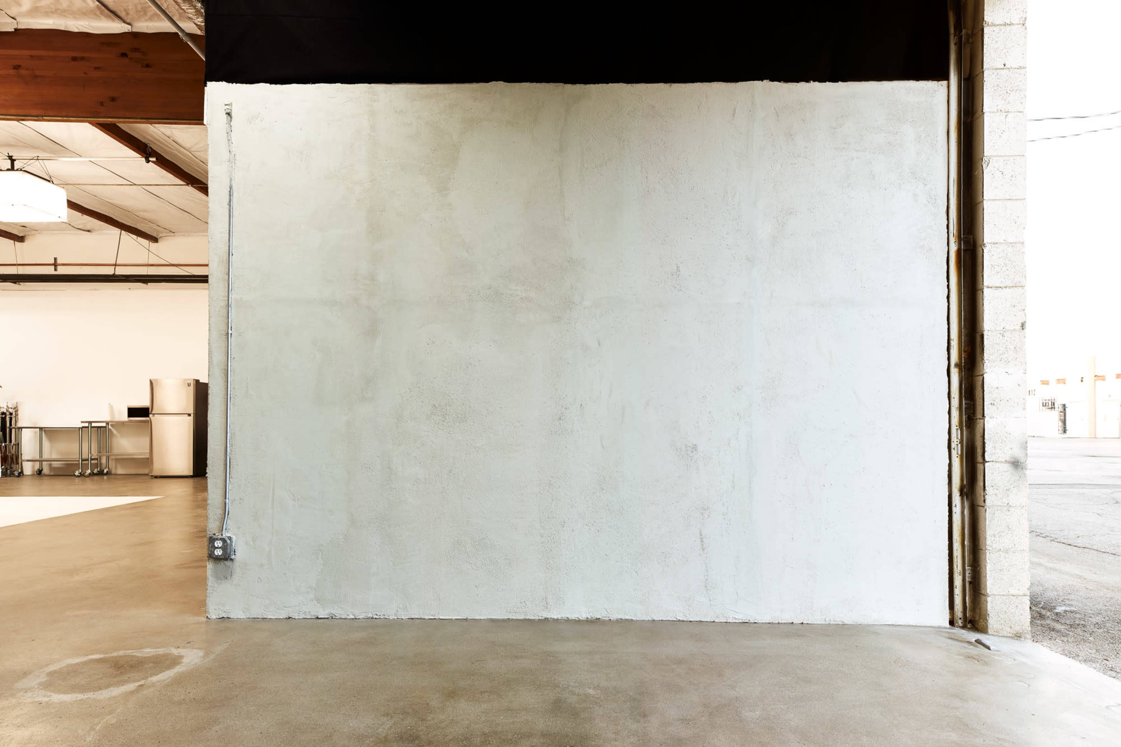 A large empty concrete wall next to an open doorway in an industrial-style space.