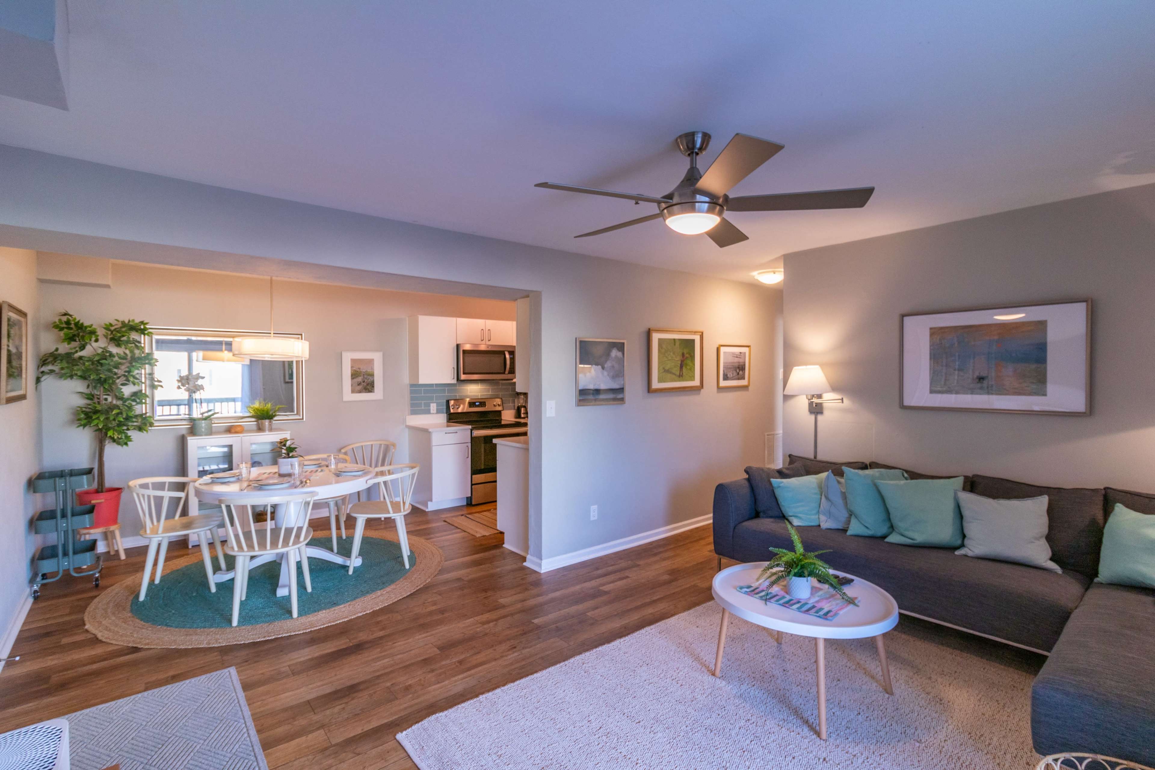 A modern living space featuring a gray sectional sofa, a round coffee table, and a dining area with a white table and chairs.