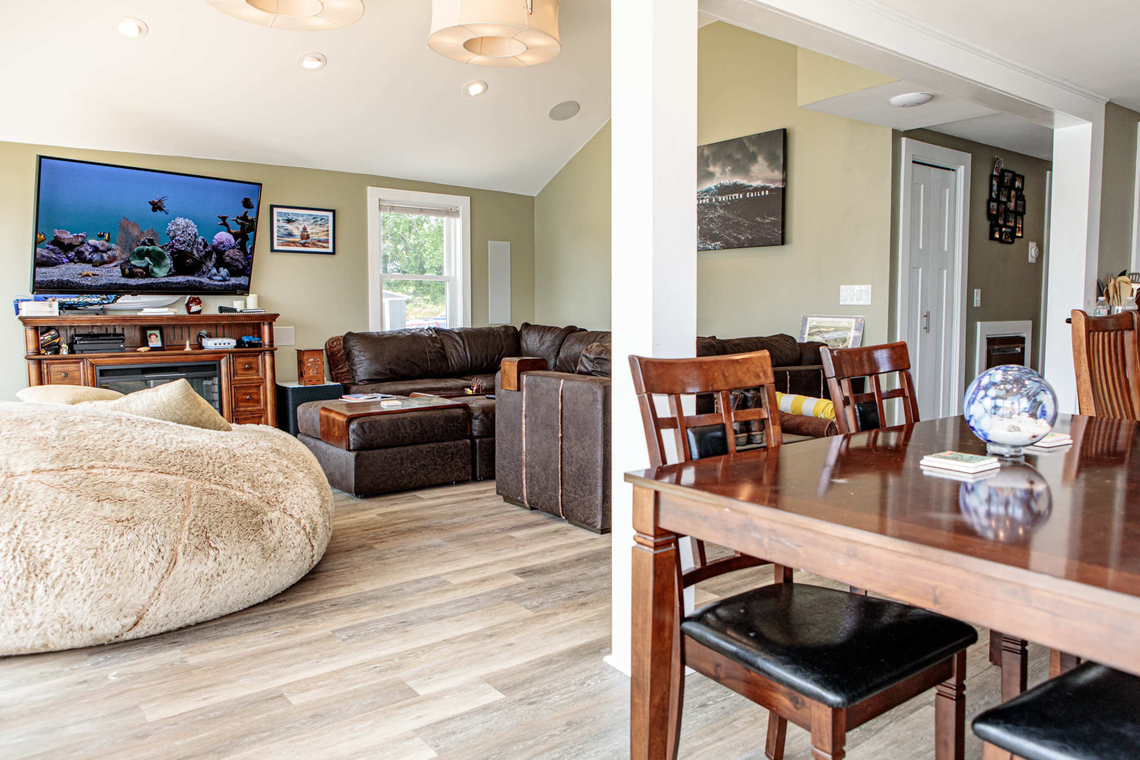 A cozy living area featuring a large bean bag chair, a television mounted on the wall, and a dining table with wooden chairs.