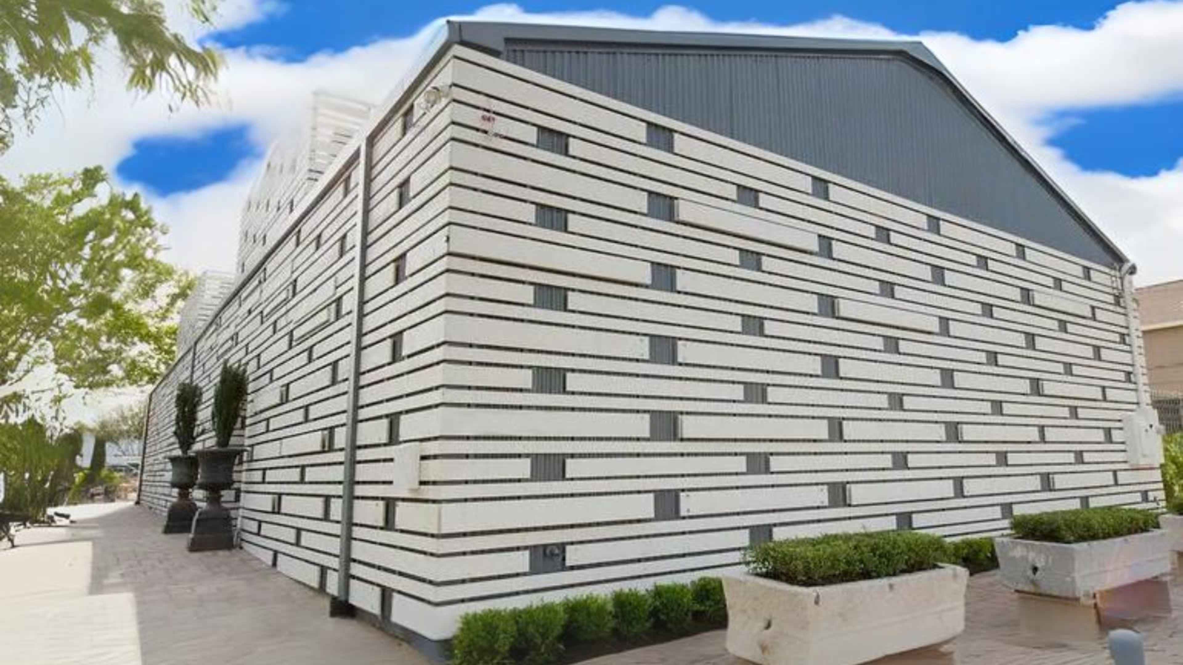 The image shows a modern building with a unique striped exterior design featuring alternating white and dark gray sections.