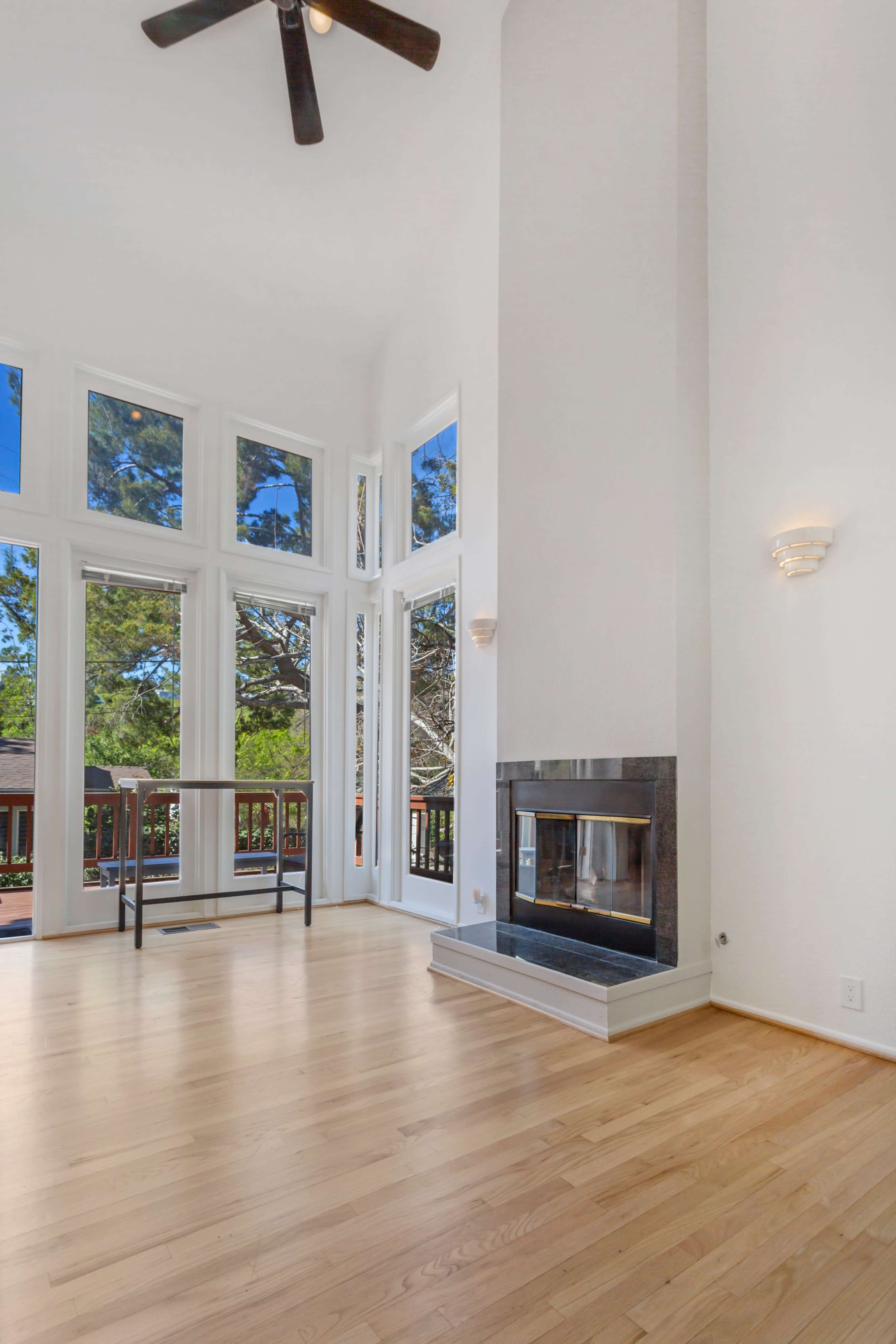 A bright living space features large windows, a modern fireplace, and hardwood floors.
