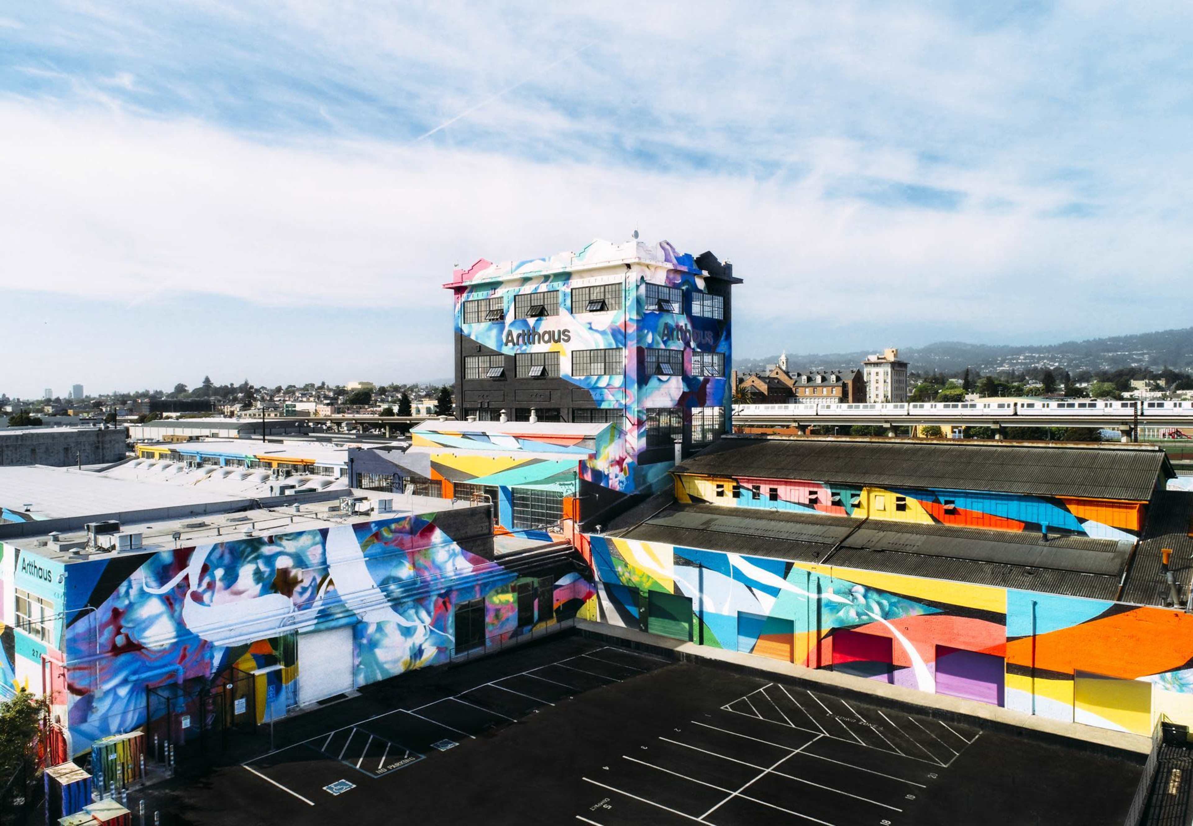 The image shows a large building complex with vibrant murals covering its exterior surfaces.