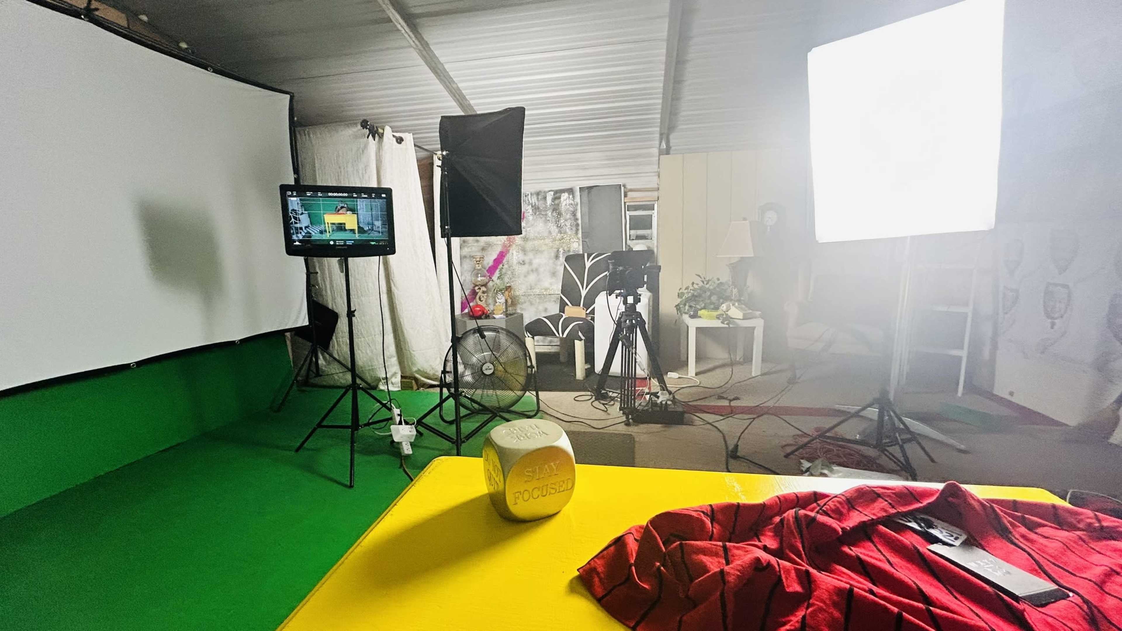 A photography studio setup with lighting equipment, a backdrop, and a table displaying a shirt and a wooden block labeled "FOCUSED."