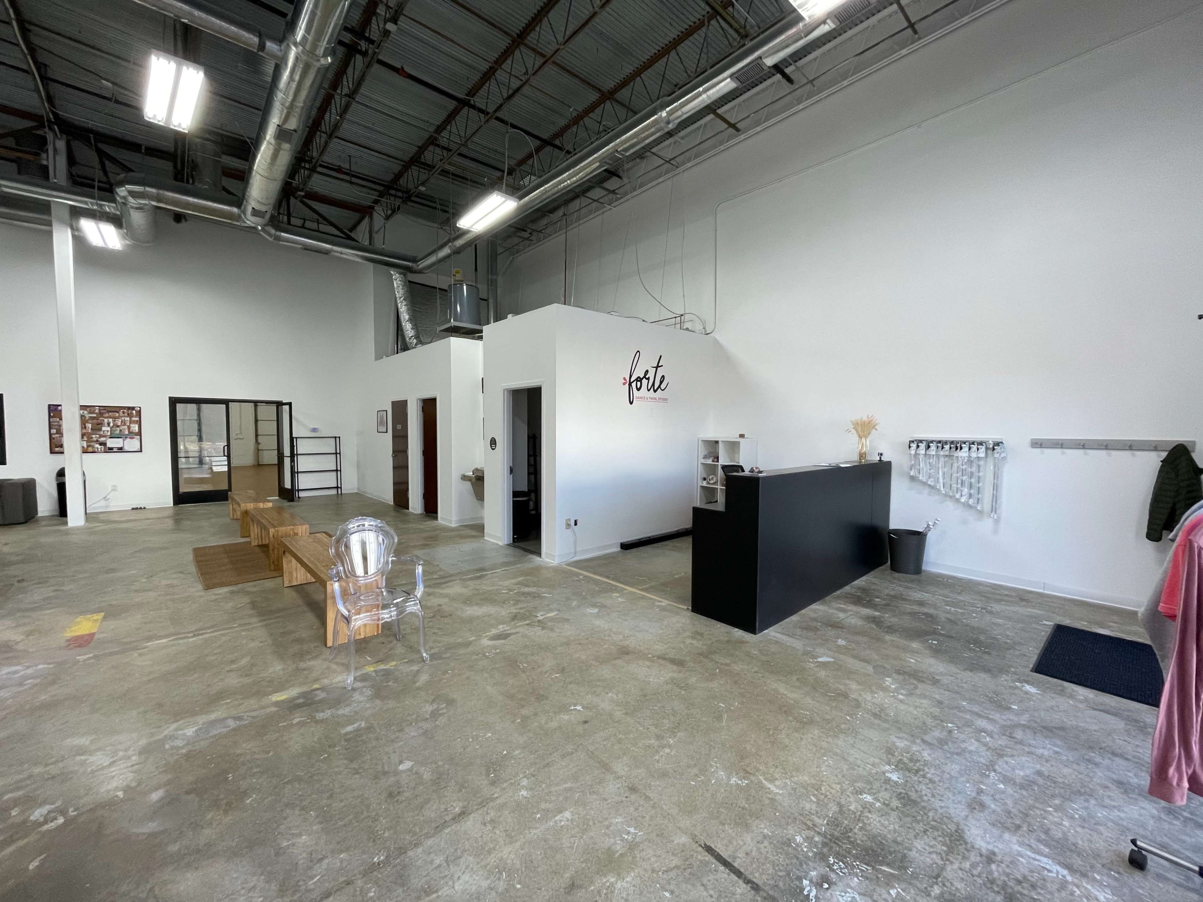 An empty commercial space with a reception area featuring a black counter and a waiting area with wooden benches.